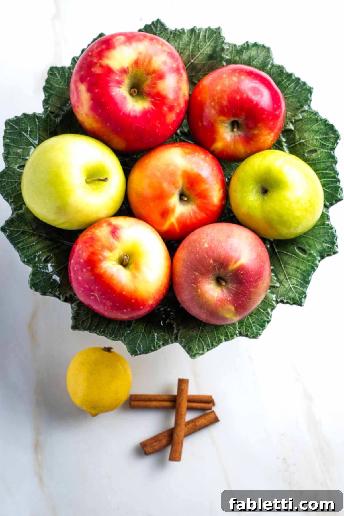 Whole apples, lemon and cinnamon sticks, the three main ingredients for applesauce.