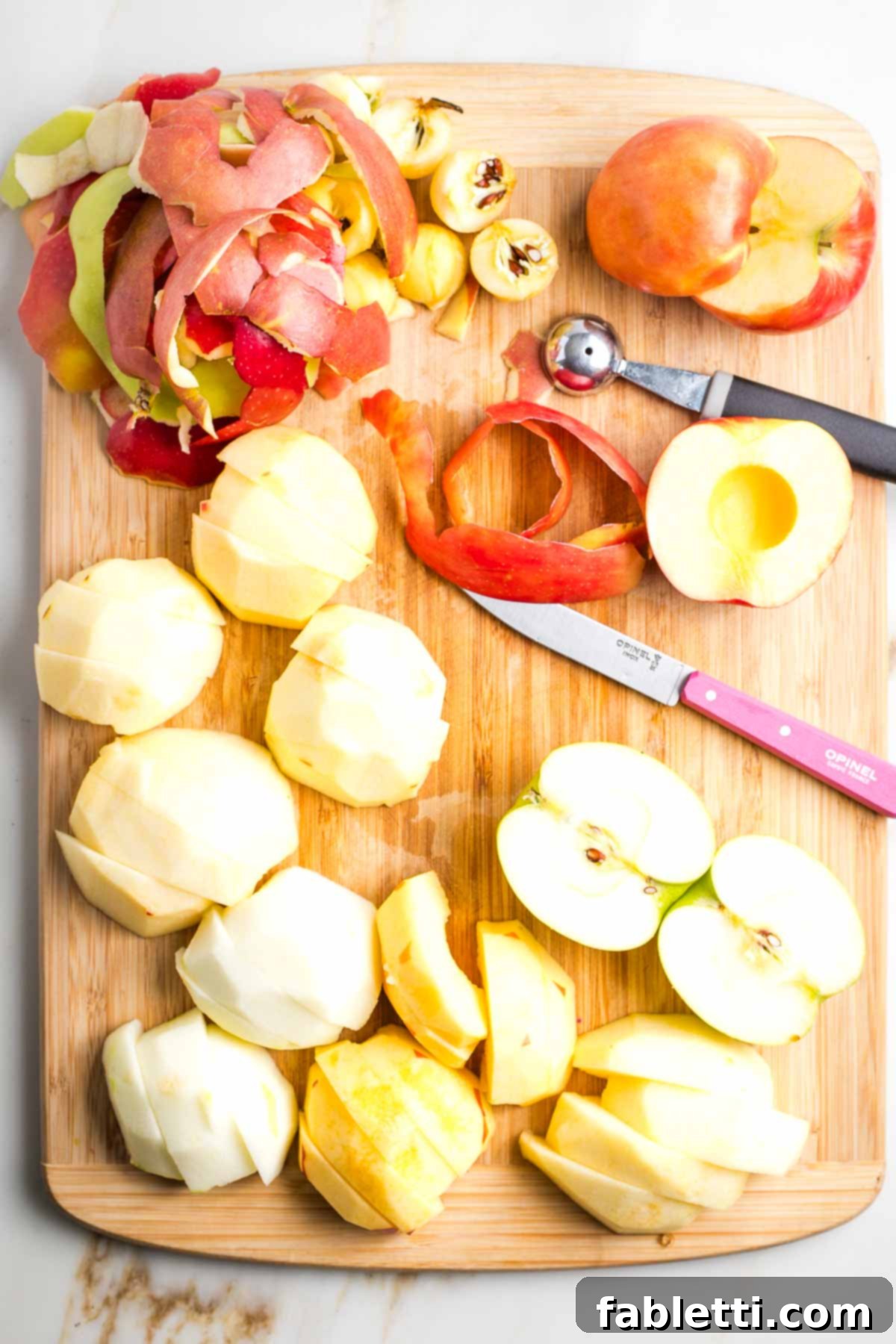 Halved apples, some peeled, some cored, and some cut into chunks, showing preparation stages.
