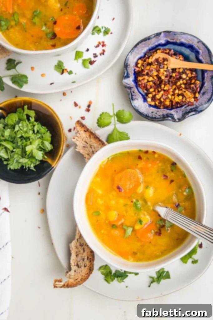 Hearty Vegan Yellow Split Pea Soup 14 A charming table setting featuring a bowl of yellow split pea soup, crusty bread, fresh chopped parsley, and crushed red pepper, creating an inviting and warm atmosphere.