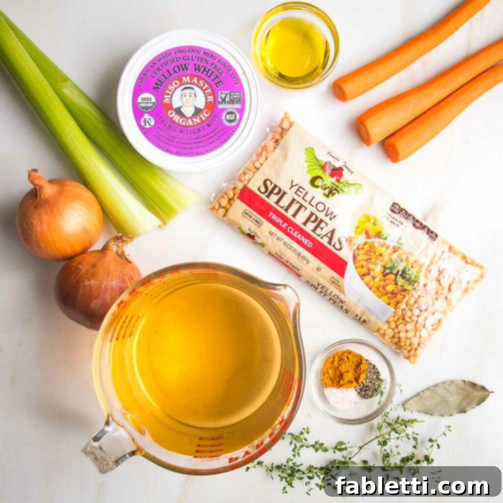 Hearty Vegan Yellow Split Pea Soup 3 Assortment of fresh and dry ingredients for yellow split pea soup, including a bag of dried yellow split peas, a container of light miso paste, fresh carrots, celery, onions, various spices, fresh thyme, a bay leaf, and a container of vegetable stock.