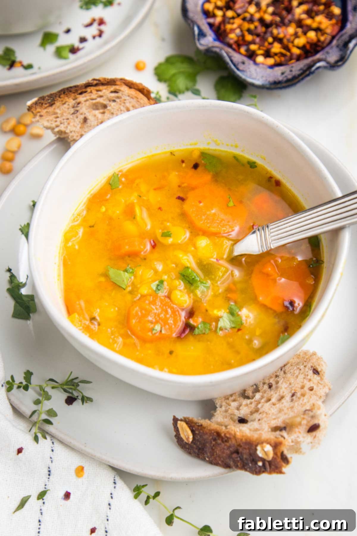 Hearty Vegan Yellow Split Pea Soup 4 A beautifully presented bowl of yellow split pea soup, accompanied by a slice of crusty bread, ready to be enjoyed.
