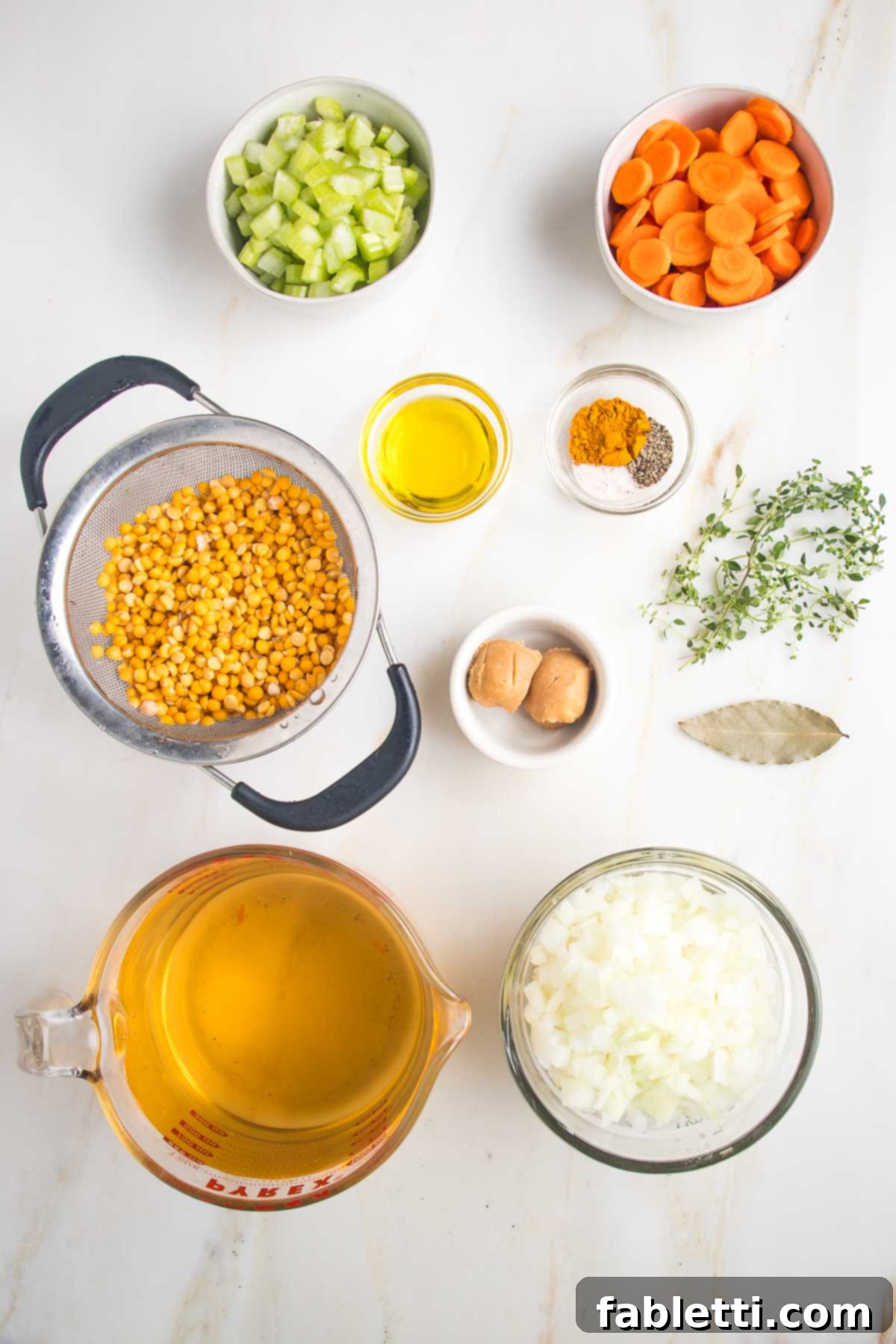 Hearty Vegan Yellow Split Pea Soup 5 Individual dishes displaying prepped split pea soup ingredients: chopped celery, carrots, and onions, thoroughly rinsed yellow split peas, a measure of olive oil, a selection of spices, light miso paste, fresh thyme sprigs, a bay leaf, and vegetable stock.