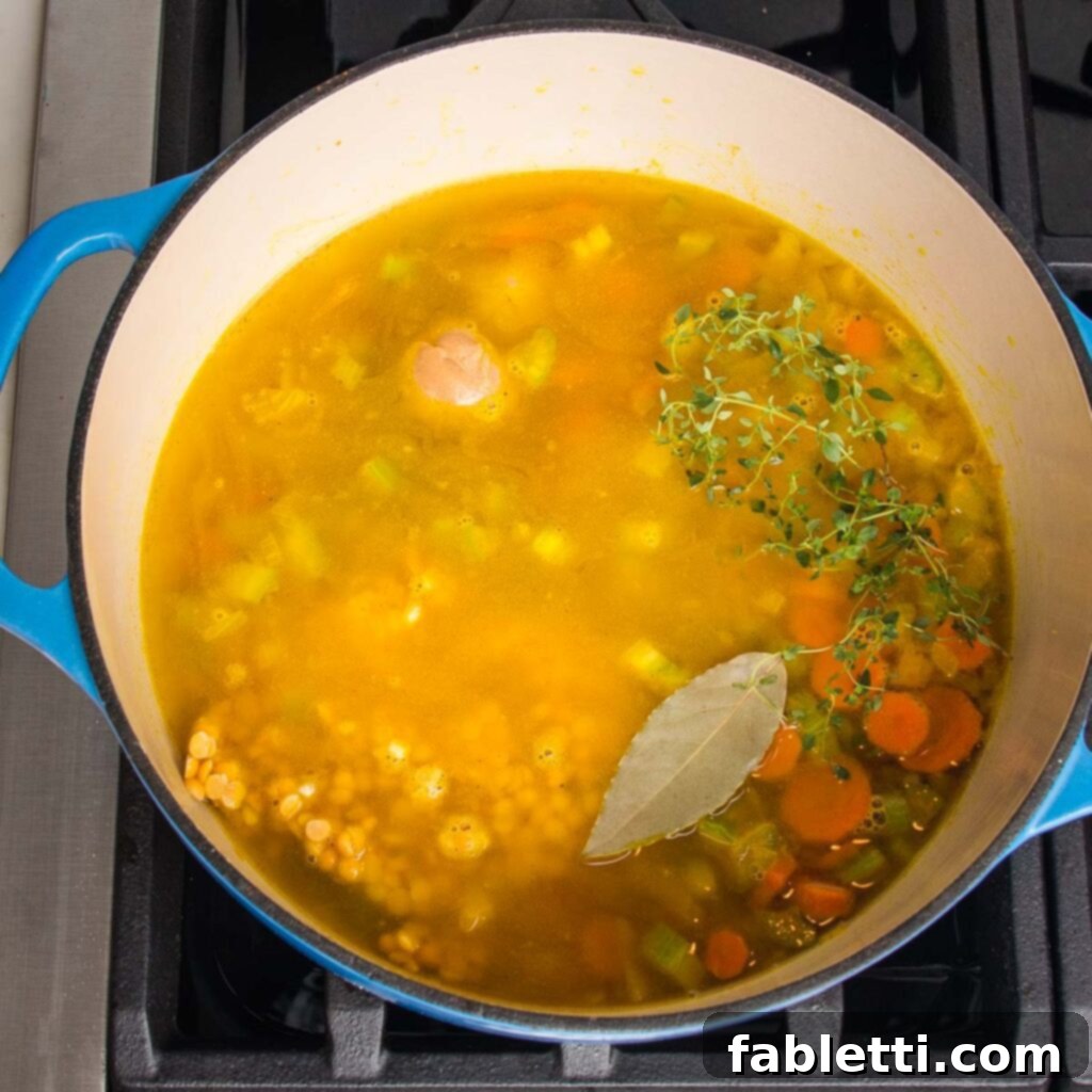 Hearty Vegan Yellow Split Pea Soup 9 Miso paste, split peas, and fresh herbs being added to the sautéed vegetables in a pot.