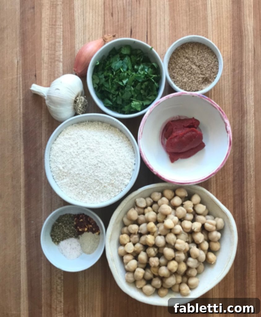 A vibrant display of fresh ingredients for vegan meatballs, including bright green parsley, whole chickpeas, rich tomato paste, shallots, garlic, and ground oats and flax seeds, all arranged with a medley of spices.