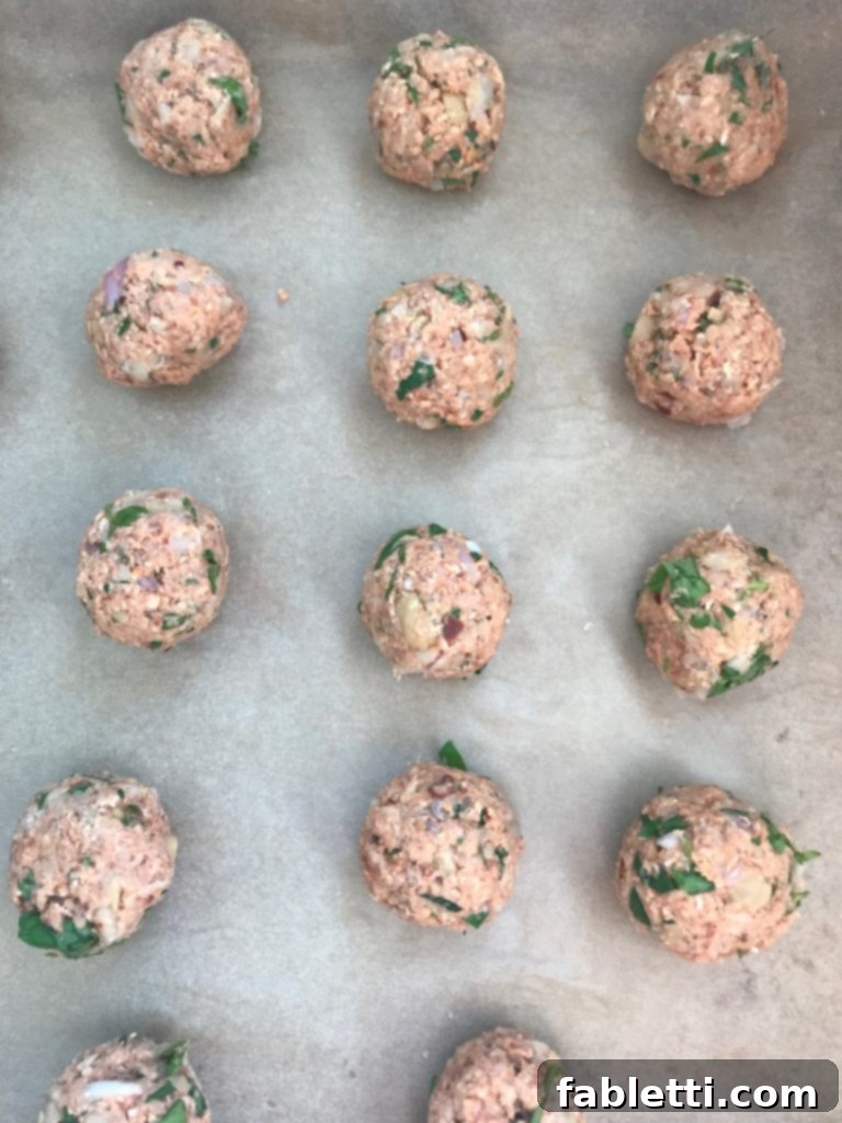 A close-up shot of perfectly rolled Vegan Sweet and Sour Meatballs, showcasing their smooth texture and appetizing shape, ready for baking.