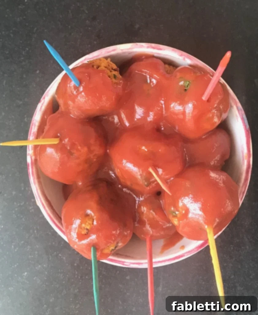 A small, inviting dish of Vegan Sweet and Sour Meatballs, beautifully plated with colorful toothpicks, hinting at a delightful and healthy party snack.