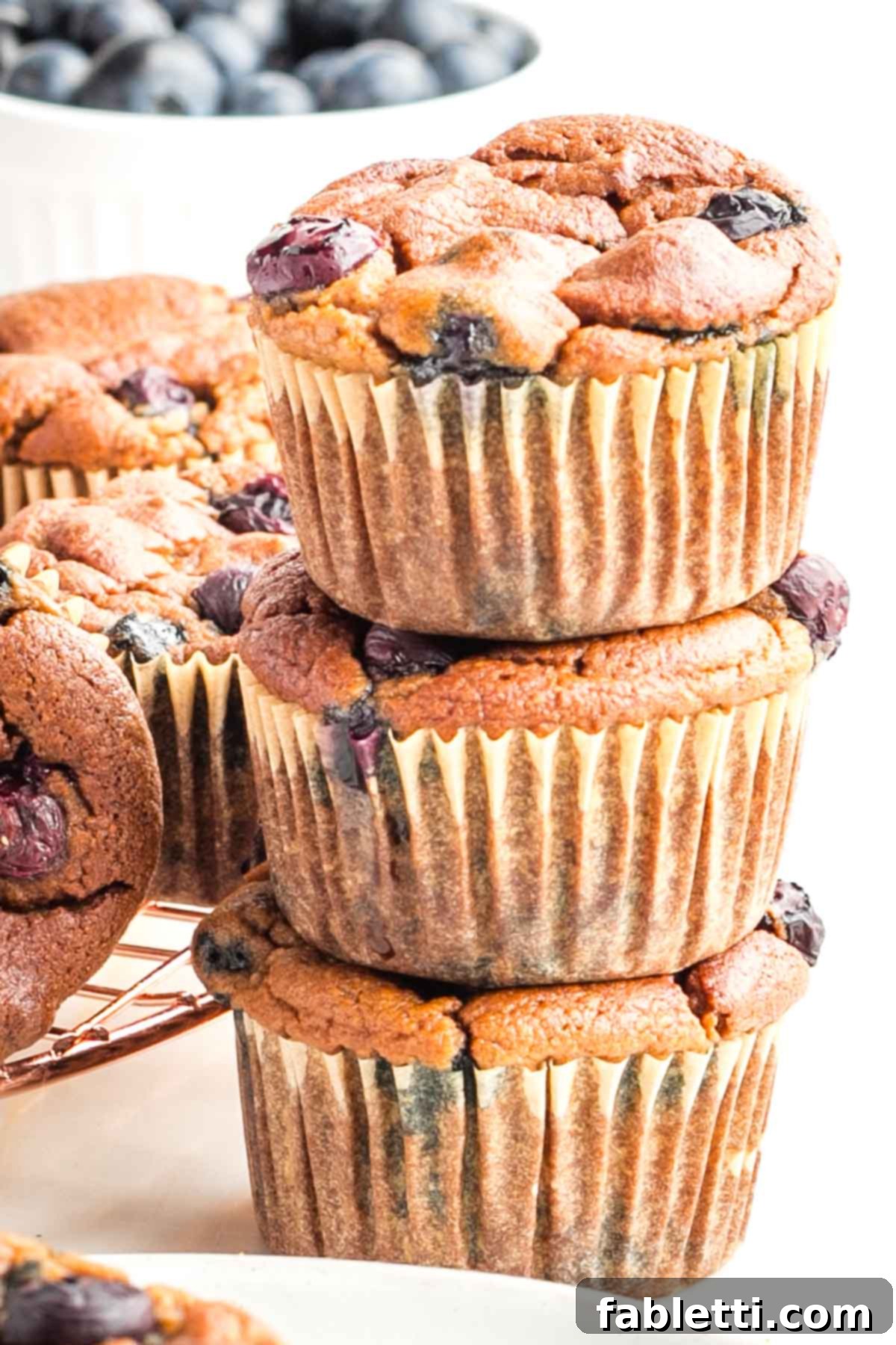 Quick Blender Almond Blueberry Muffins 4 A stack of three perfectly baked almond flour blueberry muffins, showcasing their golden-brown tops and tender texture.