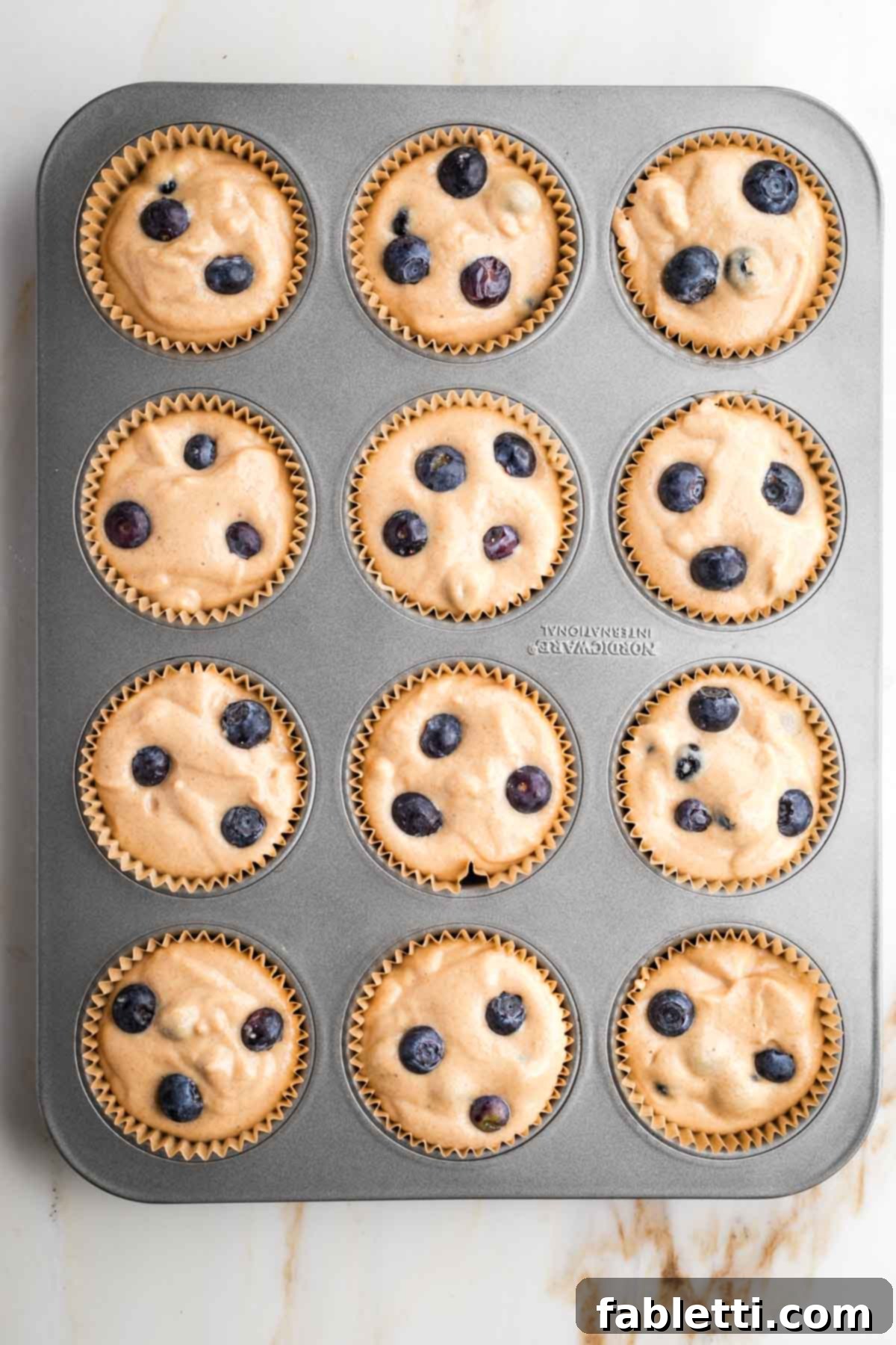 Quick Blender Almond Blueberry Muffins 7 Muffin batter evenly scooped into a prepared muffin tin, ready for baking.
