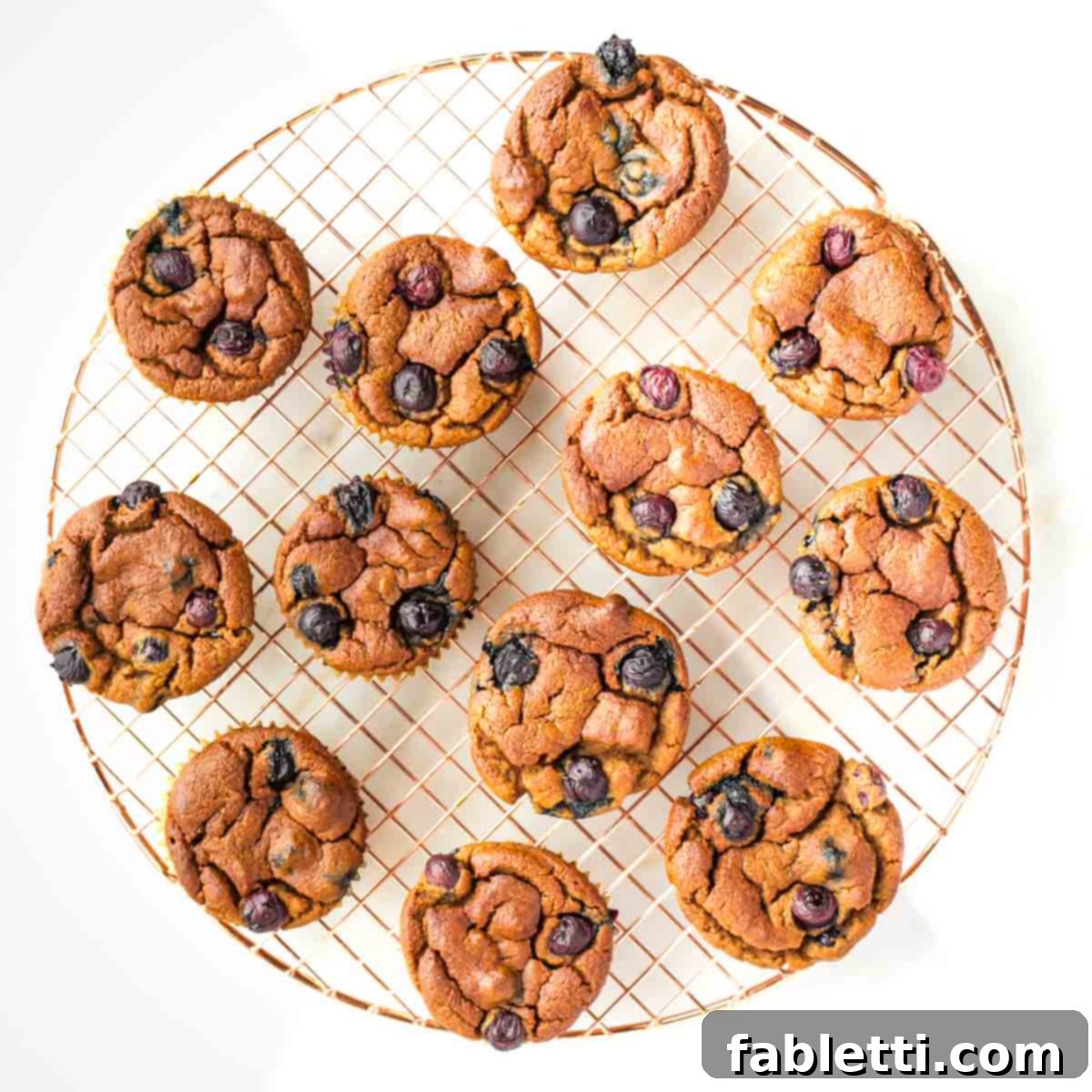 Quick Blender Almond Blueberry Muffins 9 Freshly baked gluten-free muffins cooling on a wire rack.