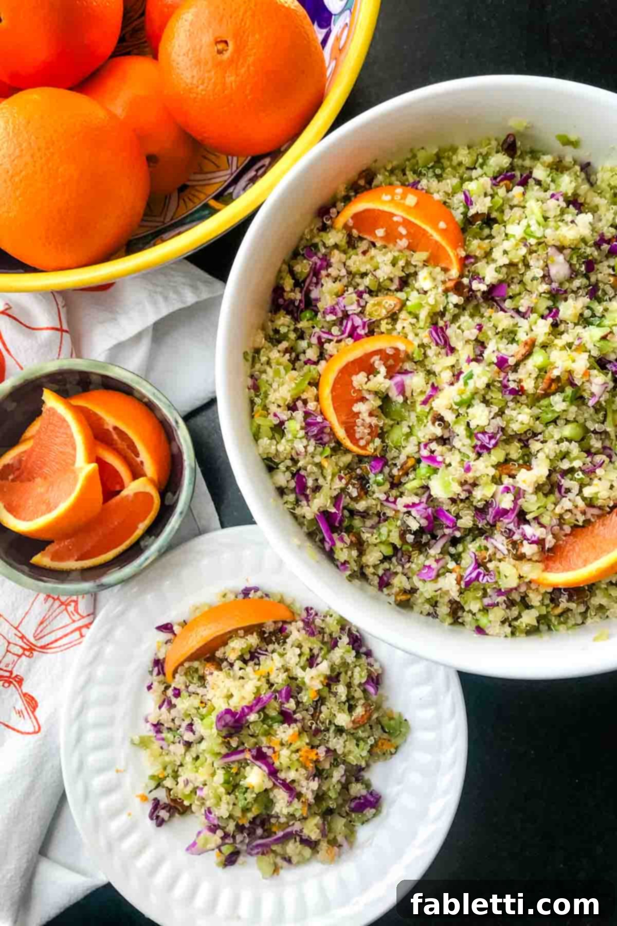 A beautifully presented bowl of riced broccoli and quinoa salad, brimming with purple cabbage, pistachios, and bright orange wedges. It’s a feast for the eyes and the palate.
