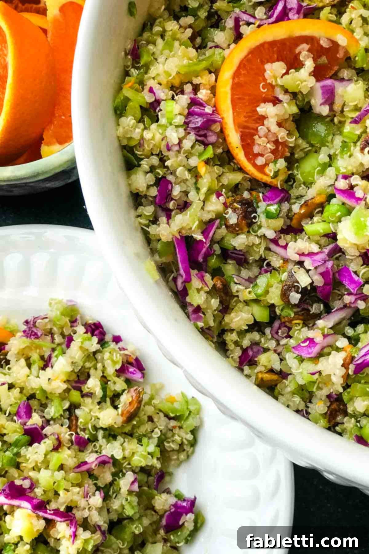A generous serving of the finished riced broccoli and quinoa salad, garnished with fresh orange wedges and bright red cabbage, ready to be enjoyed.