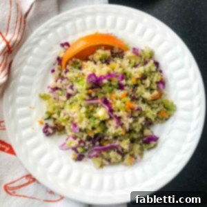 Colorful quinoa and riced broccoli salad with red cabbage and orange wedge.