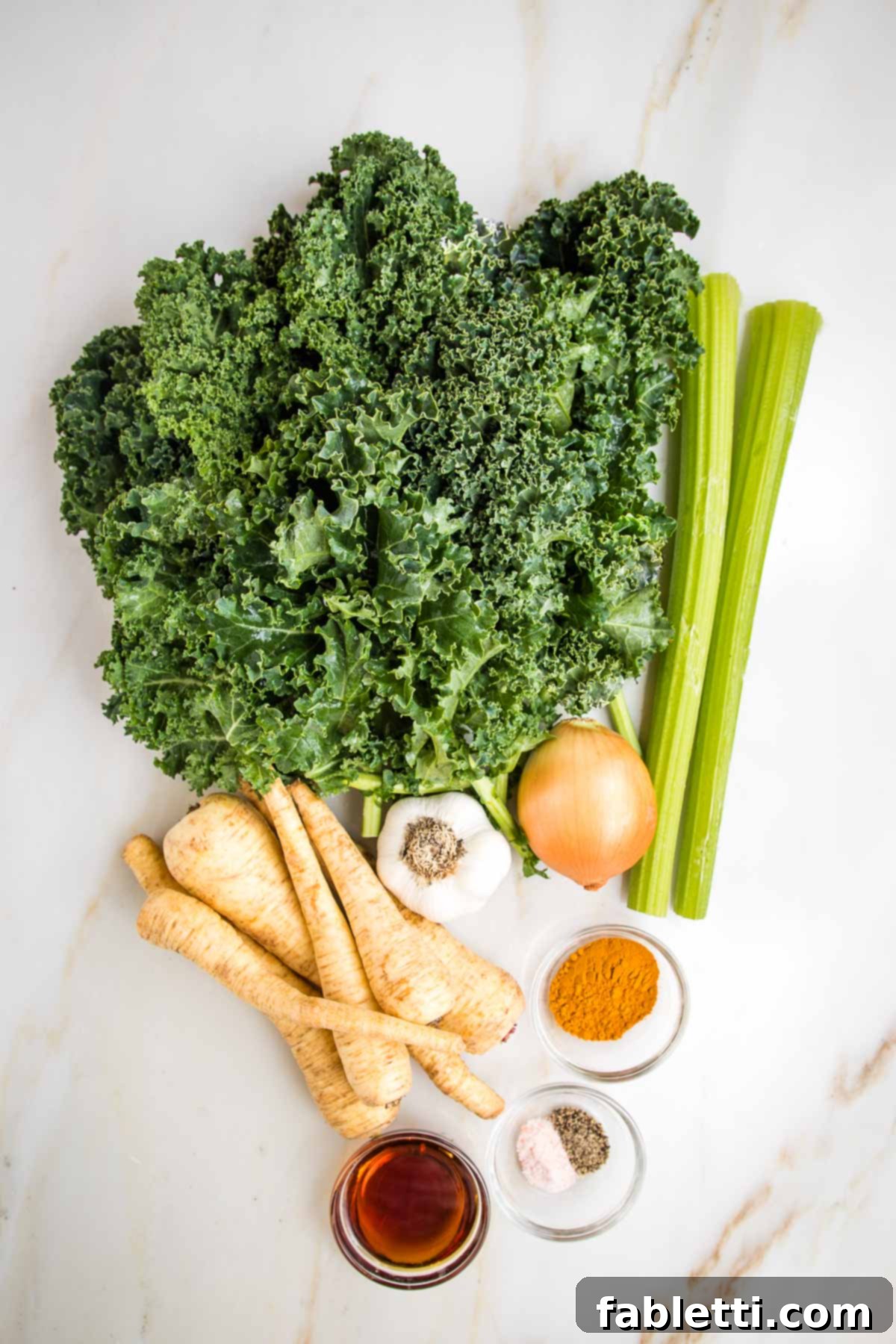 Nourishing Parsnip and Kale Soup 3 Raw ingredients for pureed vegetable soup including curly kale, celery stalks, parsnips, onion, garlic, turmeric, salt, pepper, and maple syrup.
