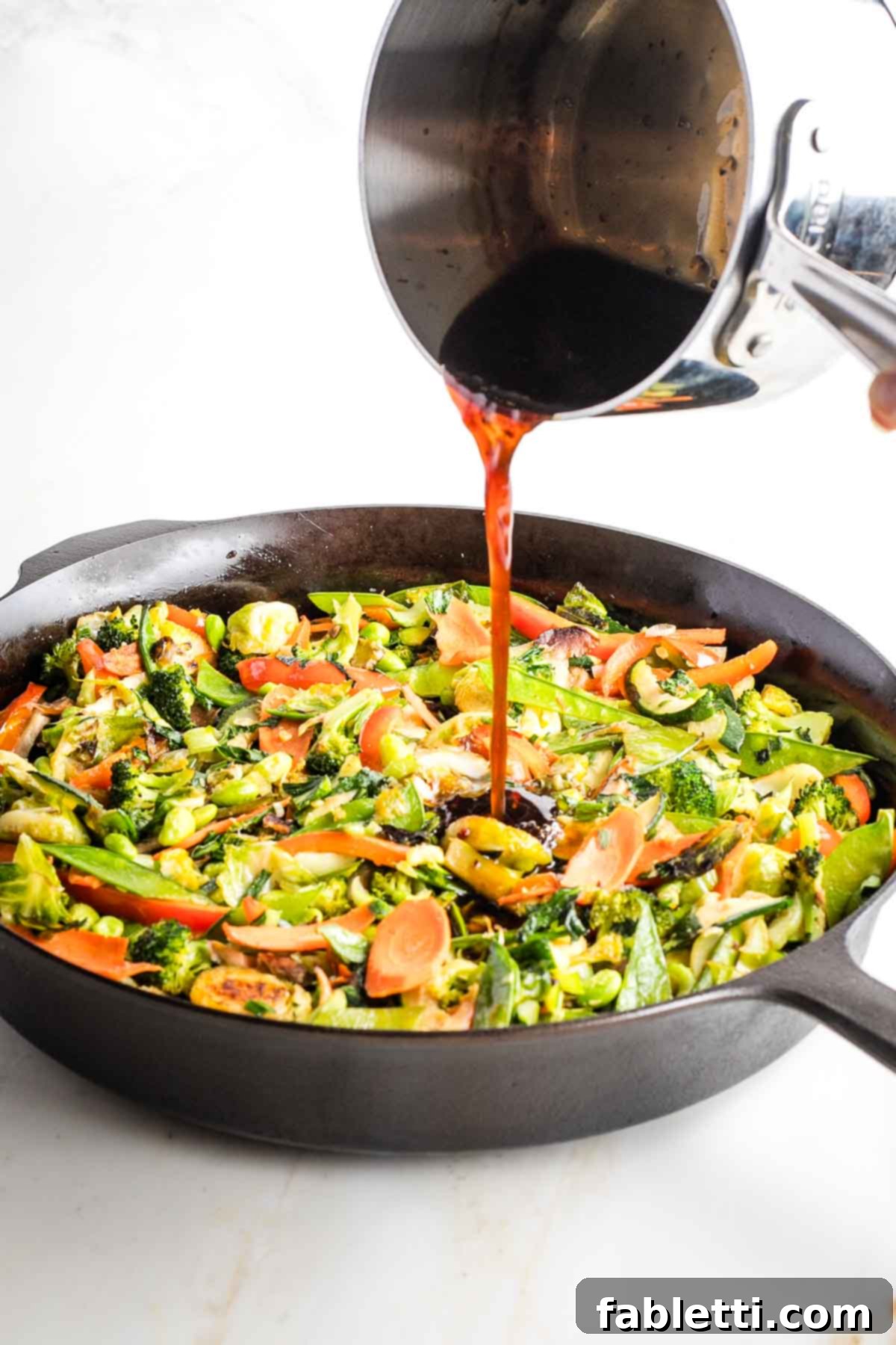 Quick and Flavorful Teriyaki Vegetable Stir-Fry 14 Reheated teriyaki sauce being poured over finished stir-fried vegetables.