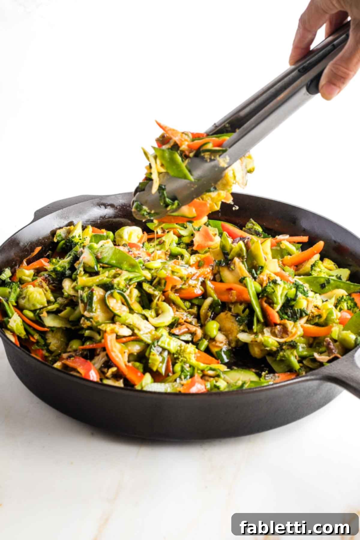 Quick and Flavorful Teriyaki Vegetable Stir-Fry 15 Tongs mixing teriyaki sauce into stir-fried vegetables.