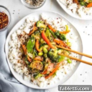 Quick and Flavorful Teriyaki Vegetable Stir-Fry 18 Plate of rice covered with vegetables and teriyaki sauce, sprinkled with sesame seeds.