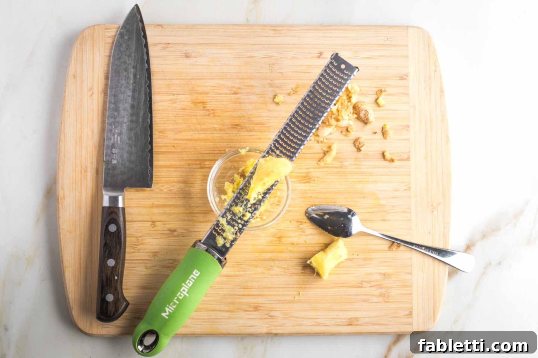 Quick and Flavorful Teriyaki Vegetable Stir-Fry 5 Grapefruit spoon peeling skin off fresh ginger and microplane grating it into a bowl.