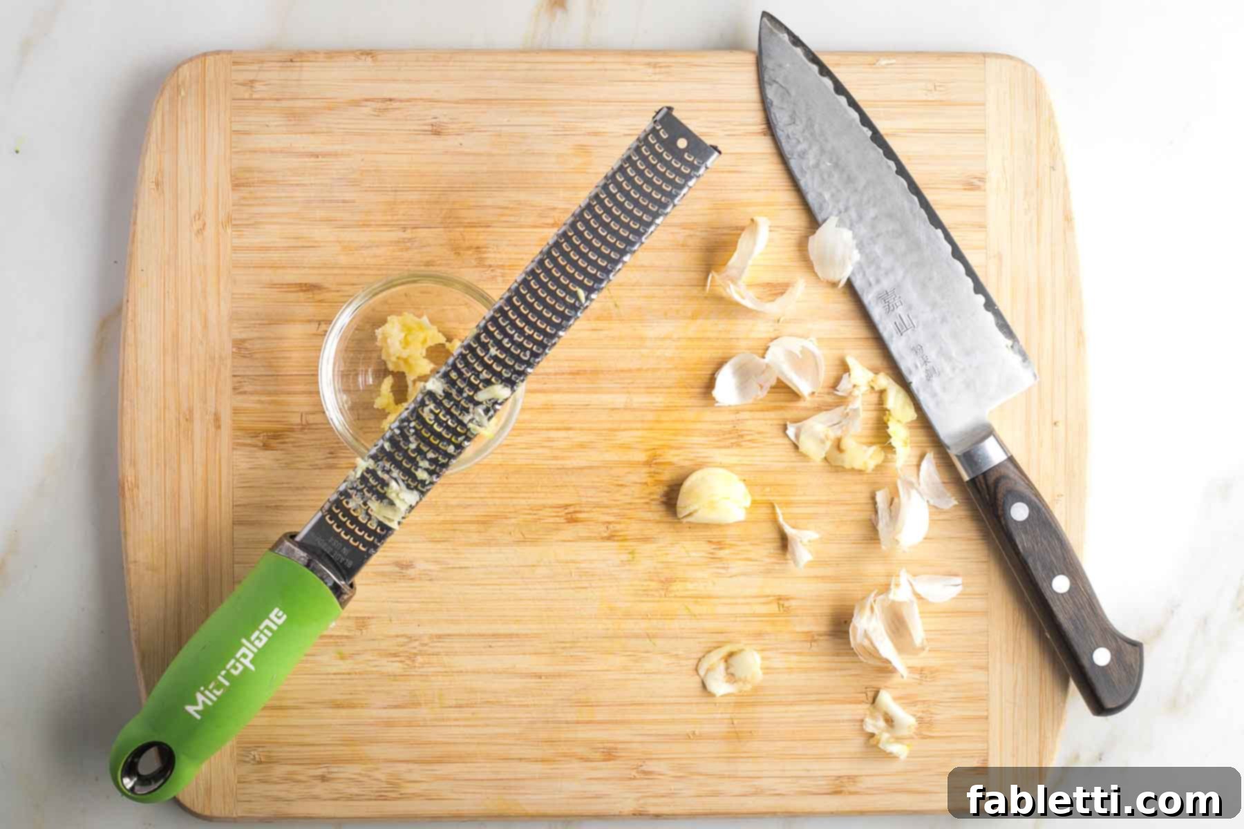 Quick and Flavorful Teriyaki Vegetable Stir-Fry 6 Peeled cloves of garlic being grated into a dish on a microplane.