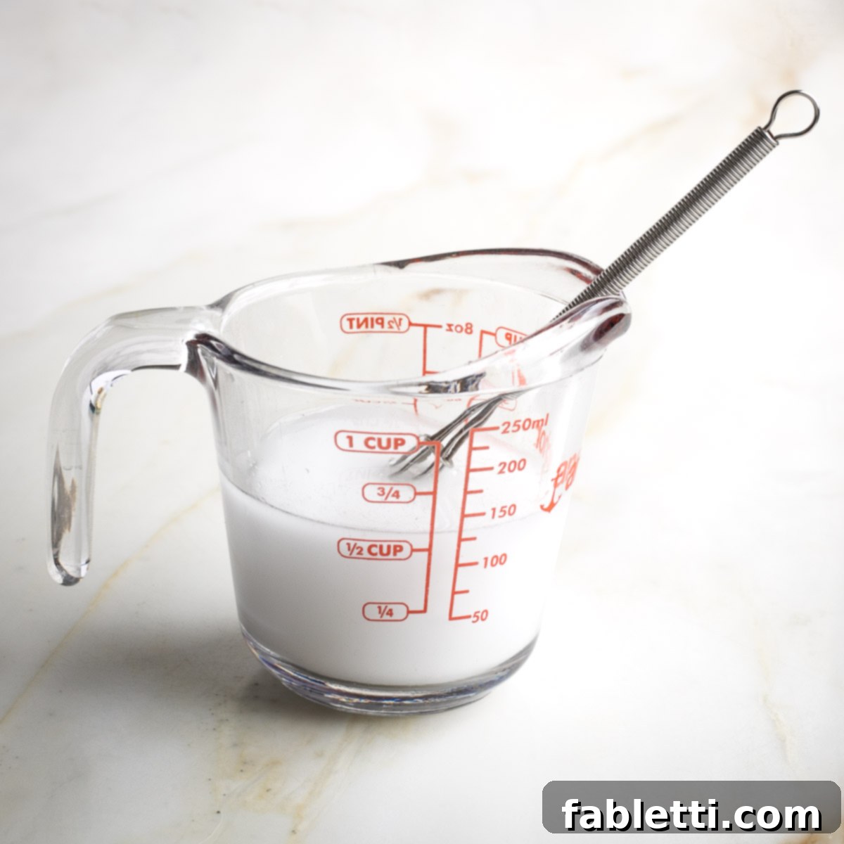 Quick and Flavorful Teriyaki Vegetable Stir-Fry 9 Pyrex measuring cup with ½ cup white liquid and a whisk.