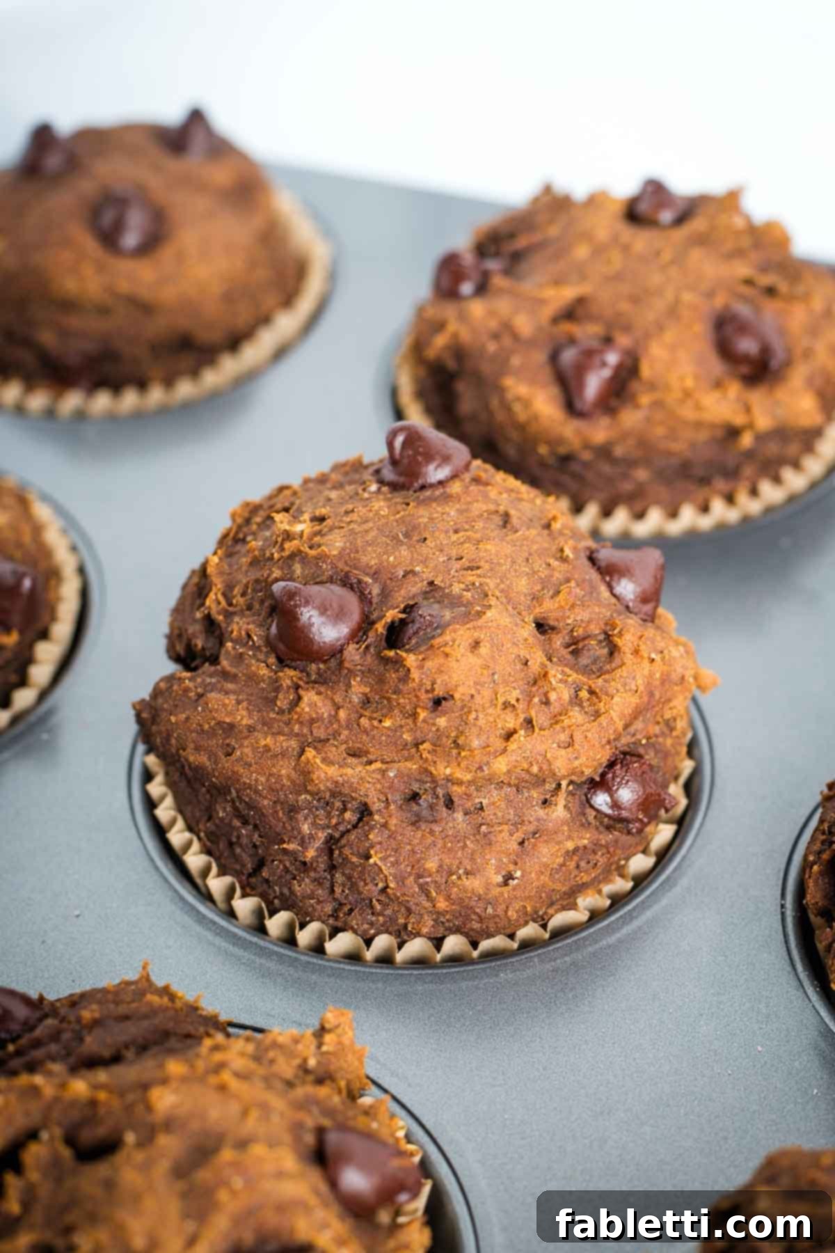 Decadent Vegan Double Chocolate Flax Muffins 12 Close up of a warm chocolate chocolate chip muffin still in the tin, showing melted chips.