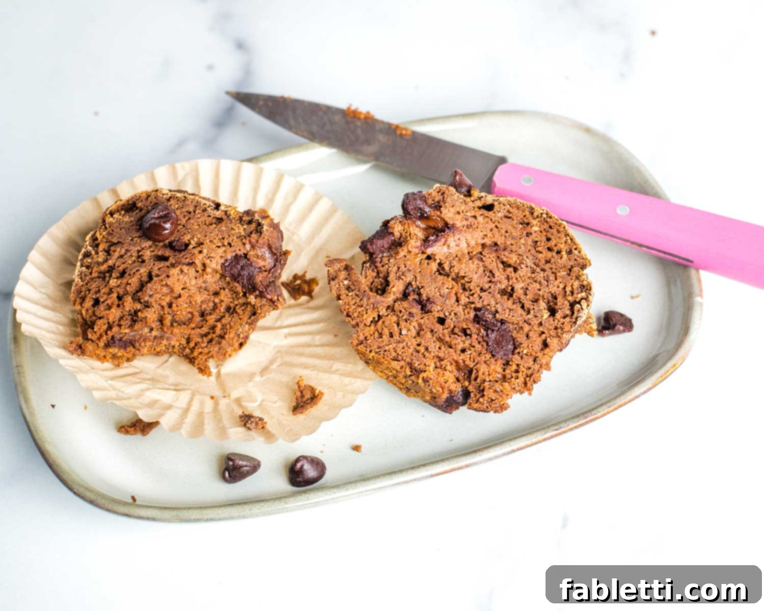 Decadent Vegan Double Chocolate Flax Muffins 14 A selection of baked vegan double chocolate muffins cooling on a wire rack, with some on a plate and a cup of coffee in the background.