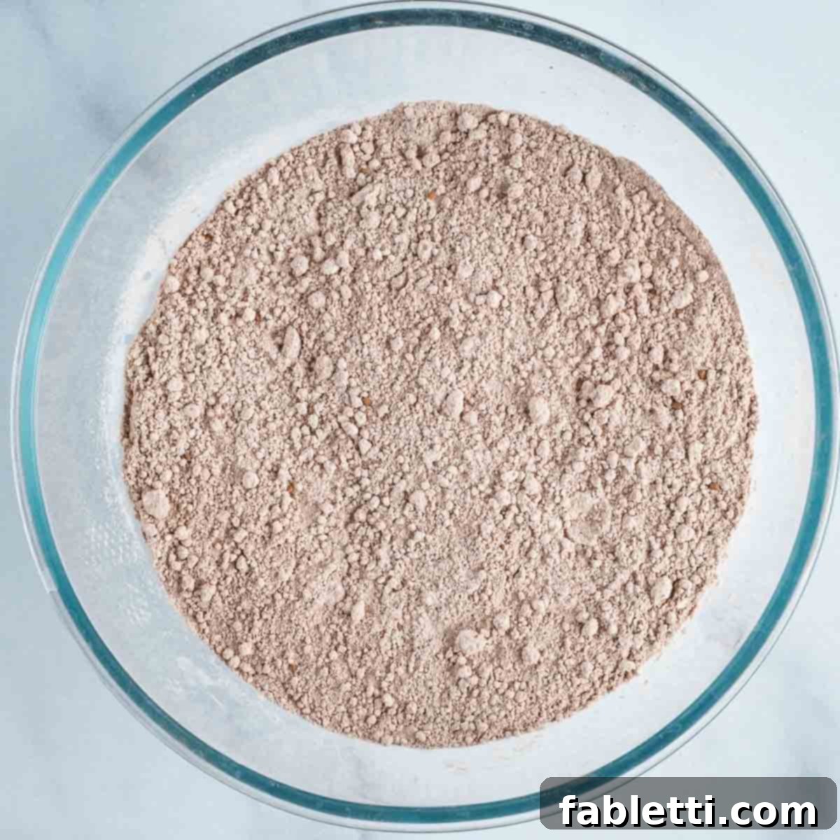 Decadent Vegan Double Chocolate Flax Muffins 5 Close-up of chocolate powdery dry ingredients mixed together in a glass bowl.