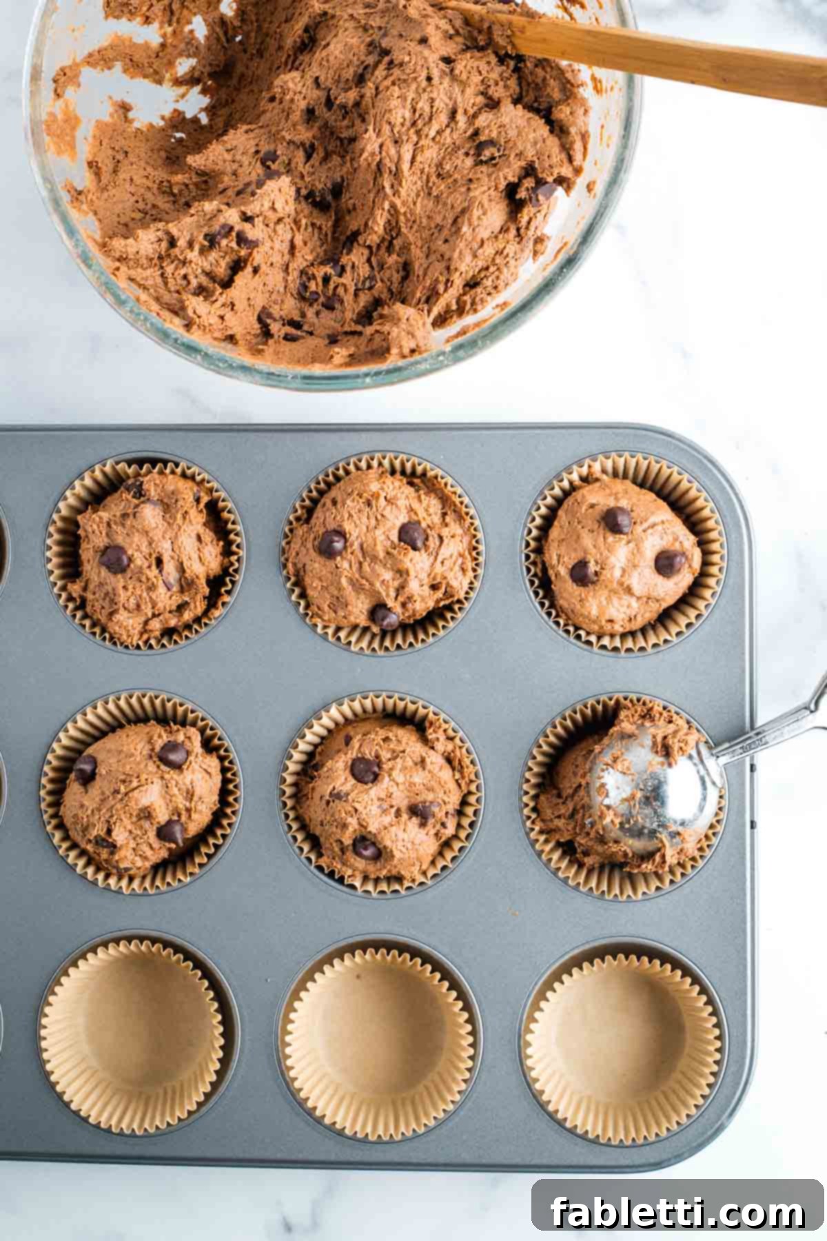 Decadent Vegan Double Chocolate Flax Muffins 10 Scooping rich chocolate chocolate chip muffin batter into parchment lined muffin tins with a cookie scoop.