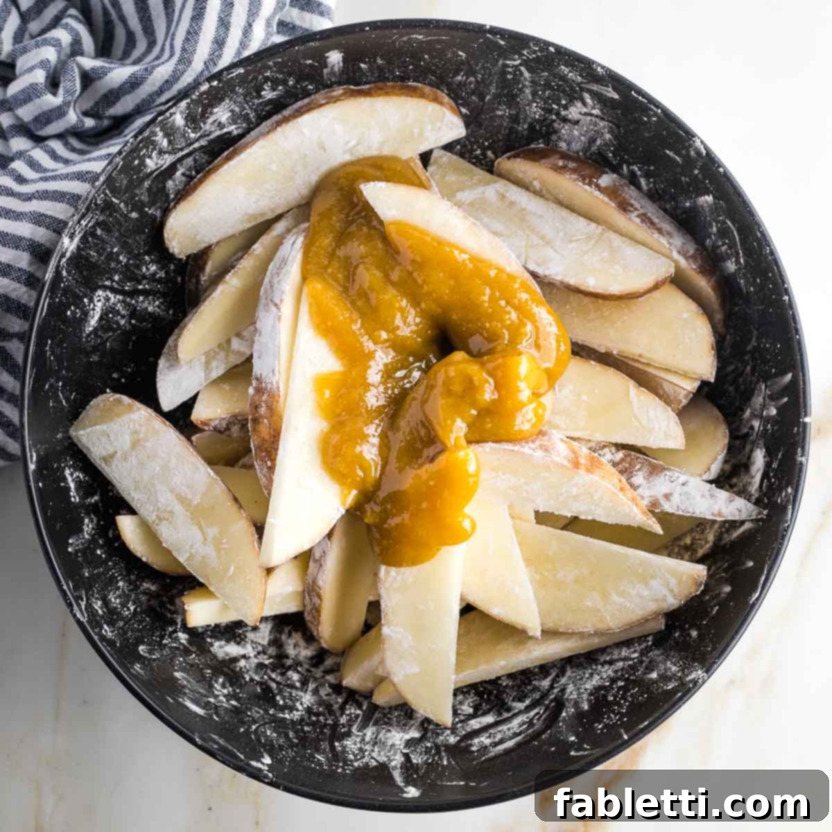 Golden Miso Crunch Potatoes 11 Bowl of potato wedges coated in arrowroot with a miso mixture on top.