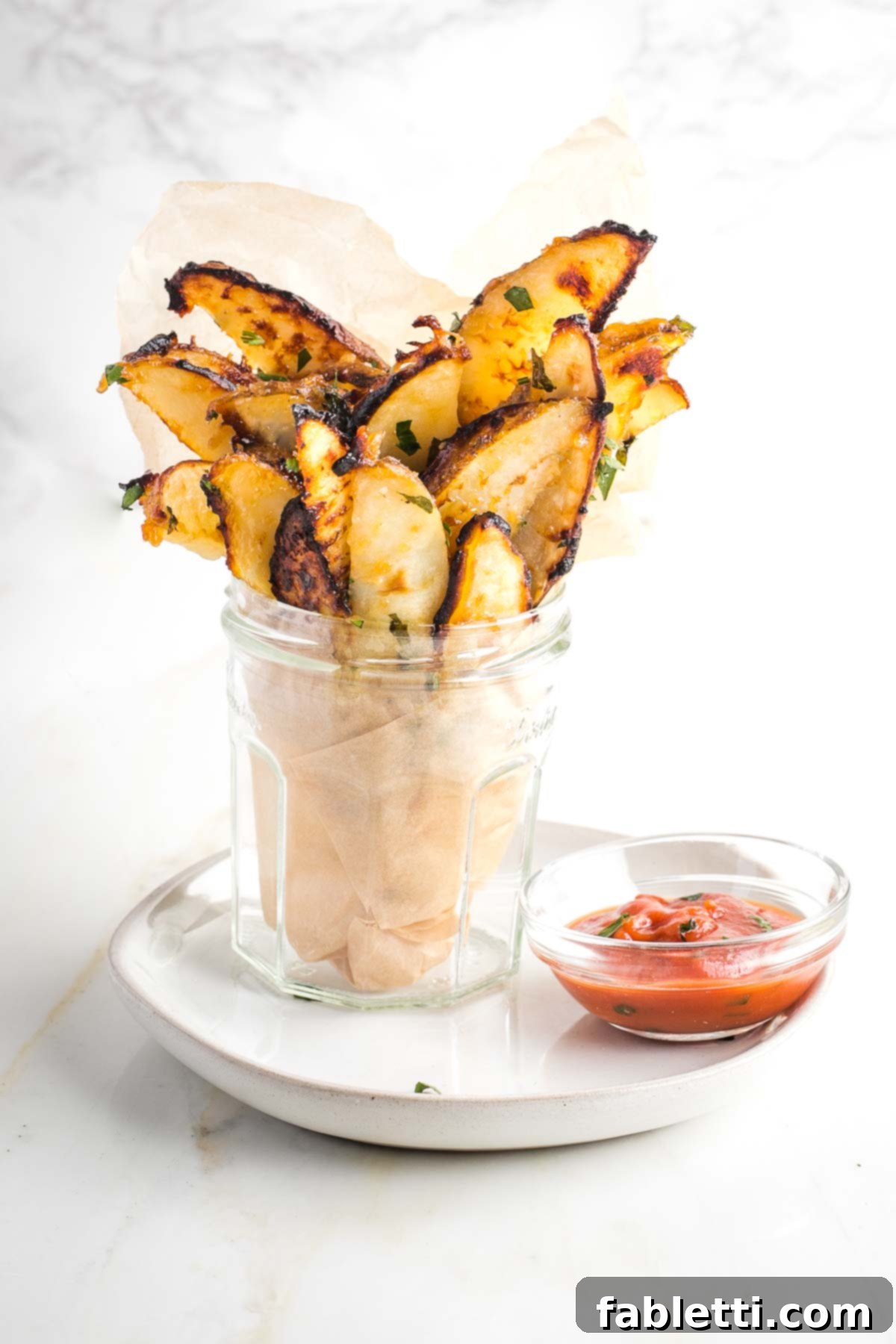 Golden Miso Crunch Potatoes 15 Glass filled with crispy fries and a small dish of ketchup.