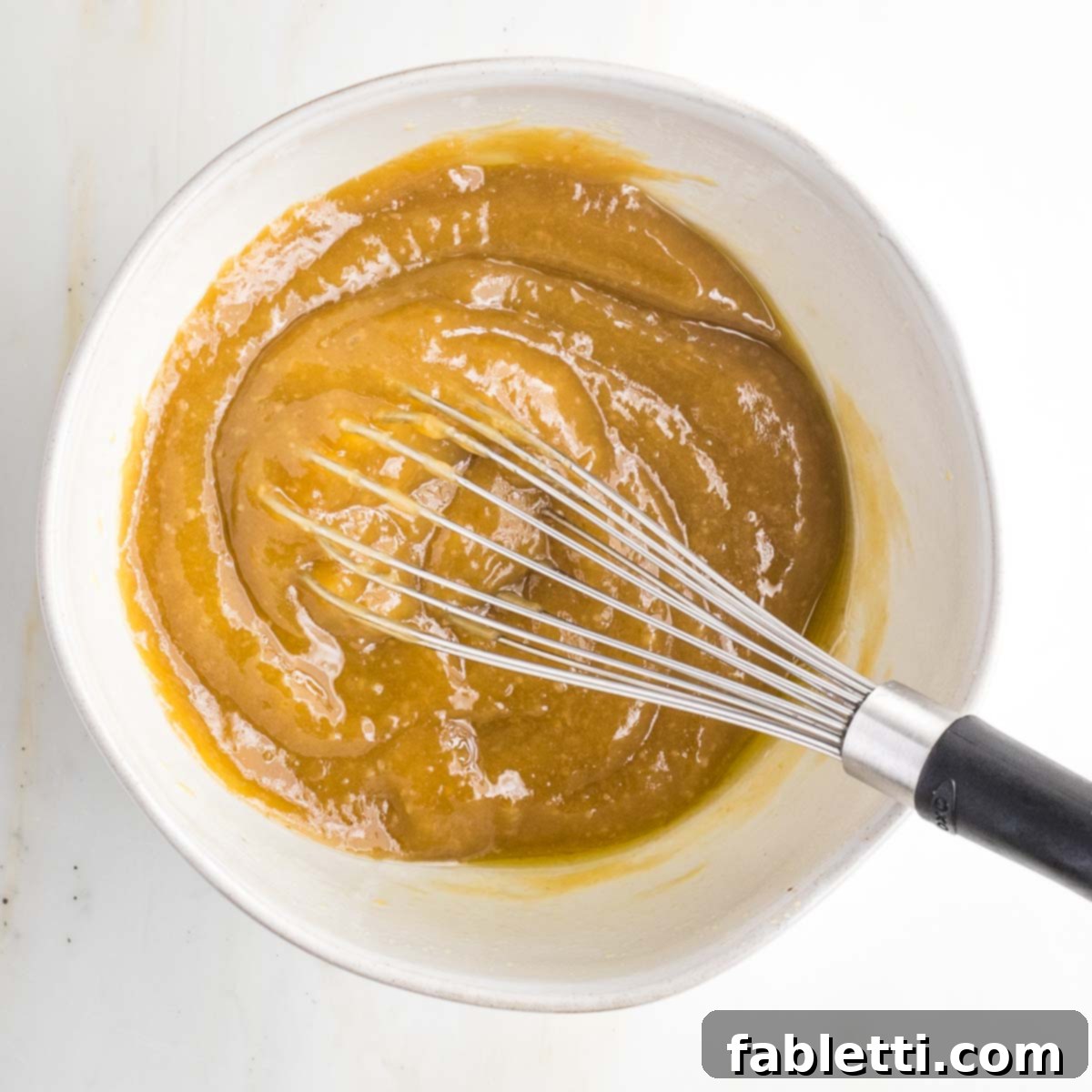 Golden Miso Crunch Potatoes 7 Bowl with whisk and pasty caramel colored mixture.