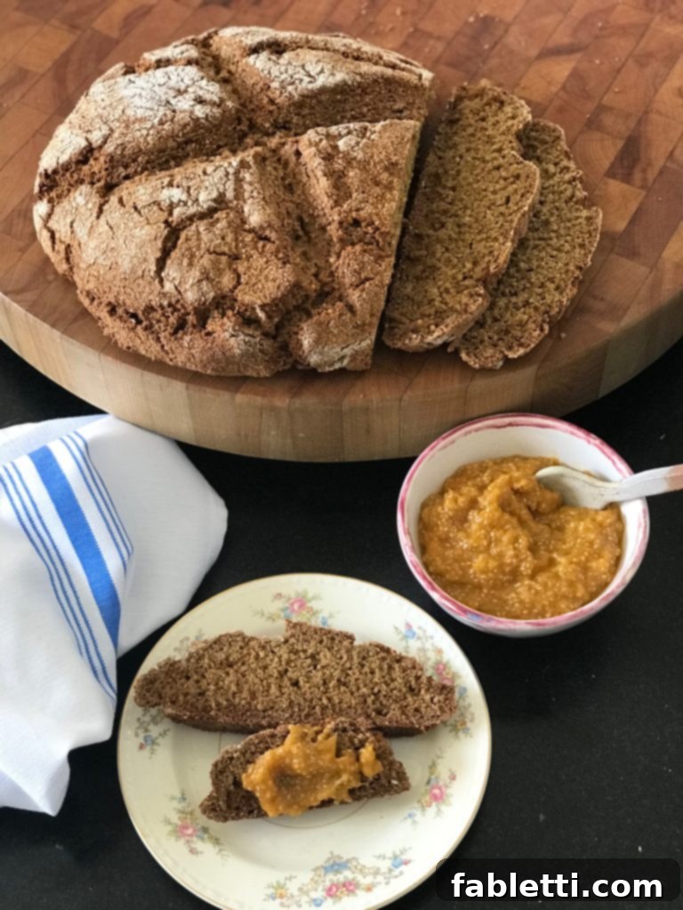Wholesome Irish Brown Bread 2 Dark, rustic whole grain Irish soda bread loaf with a dollop of vibrant orange marmalade on the side.