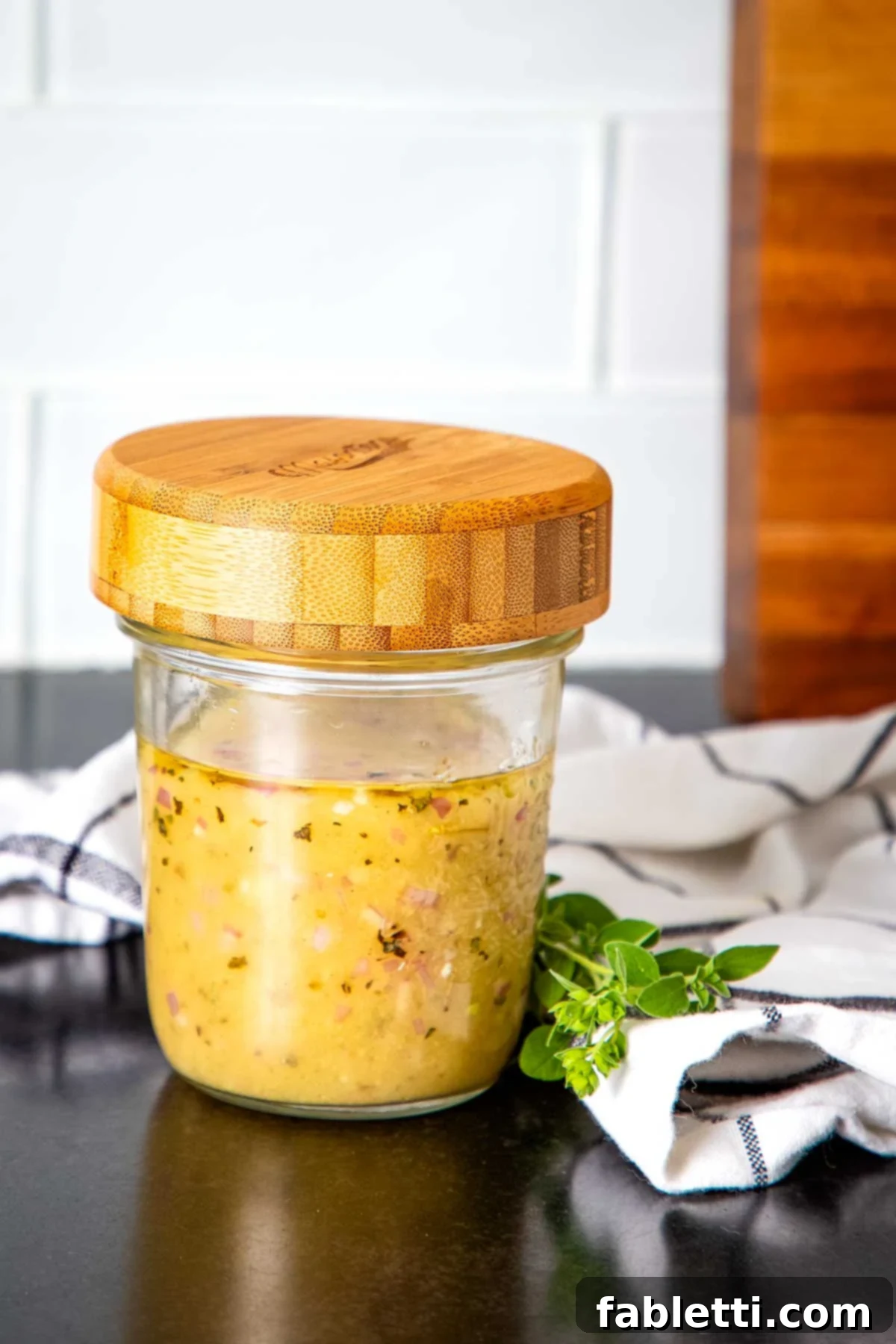 Effortless Everyday Salad Dressing 2 A jar of yellowish salad dressing with visible pieces of minced onion and spices, ready to elevate any dish.
