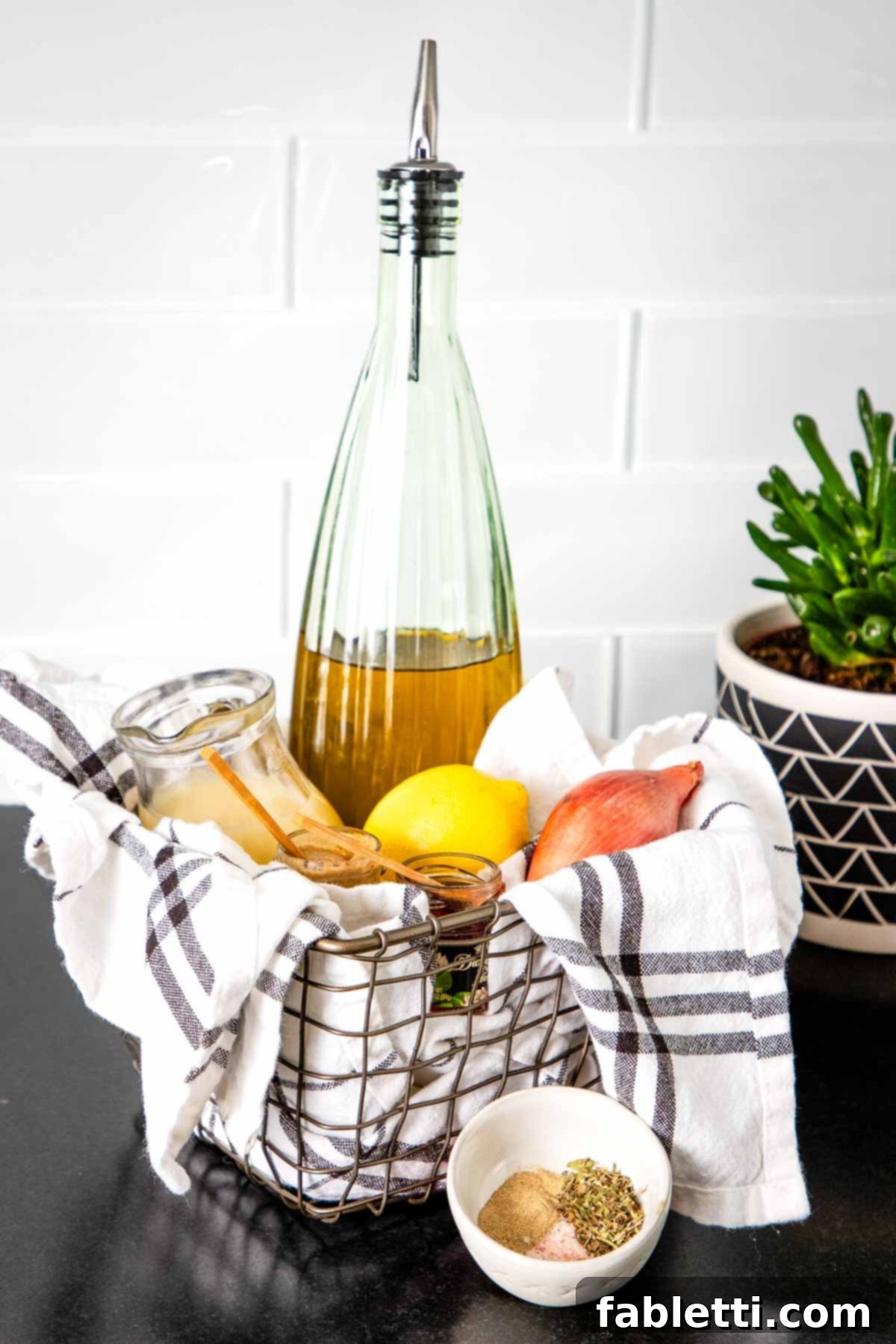 Effortless Everyday Salad Dressing 3 A rustic basket filled with fresh ingredients for making salad dressing: a bottle of olive oil, vibrant lemons, a shallot, and an array of dried spices.