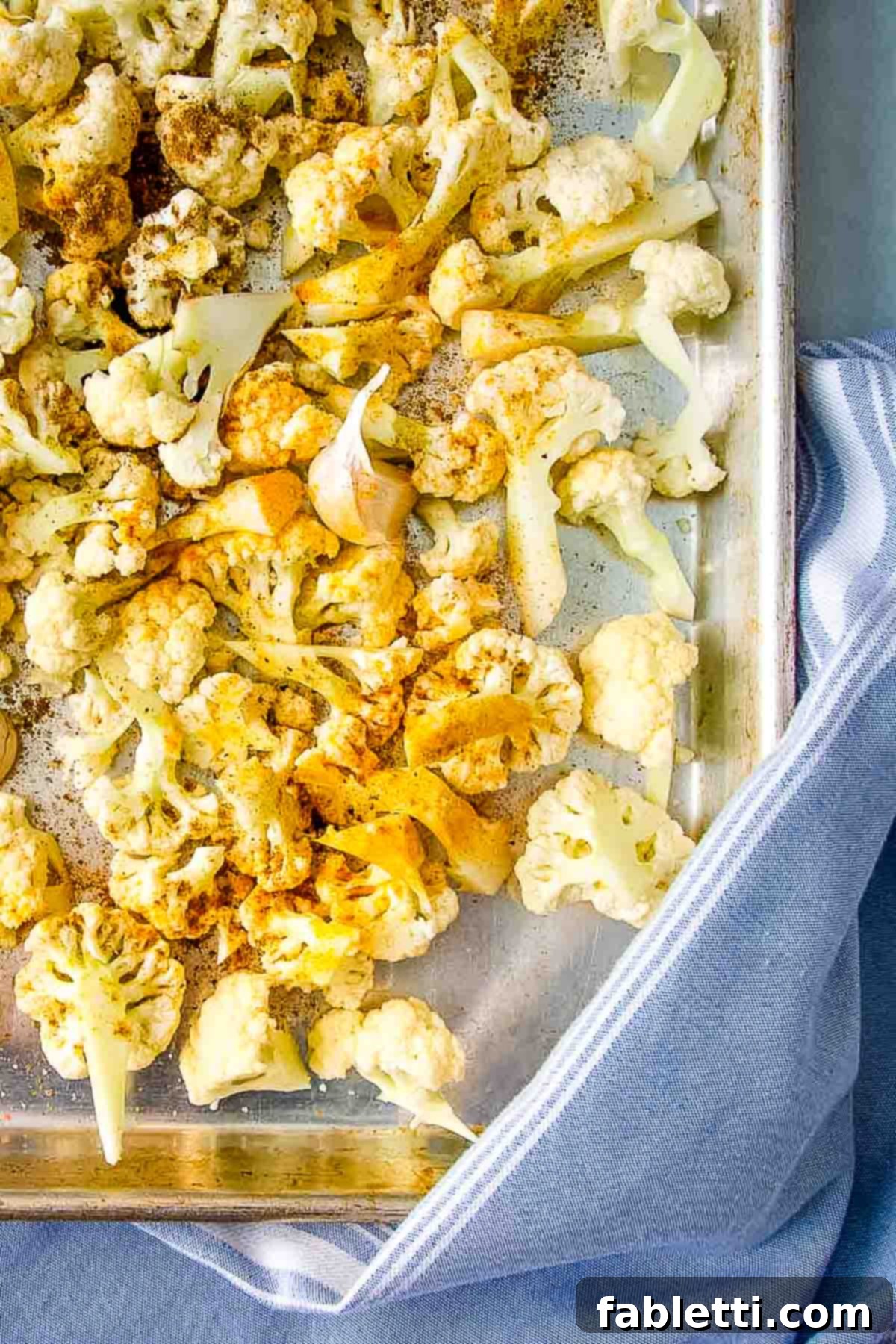 Smoky Roasted Cauliflower Hummus 5 Cauliflower florets with spices on a large rimmed baking sheet.