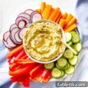 Smoky Roasted Cauliflower Hummus 9 Bowl of hummus surrounded by colorful sliced veggies.