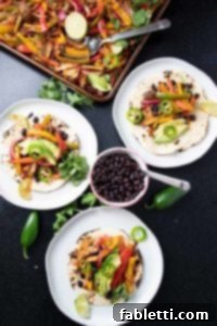 Roasted veggies on top of tortillas with bean and avocado