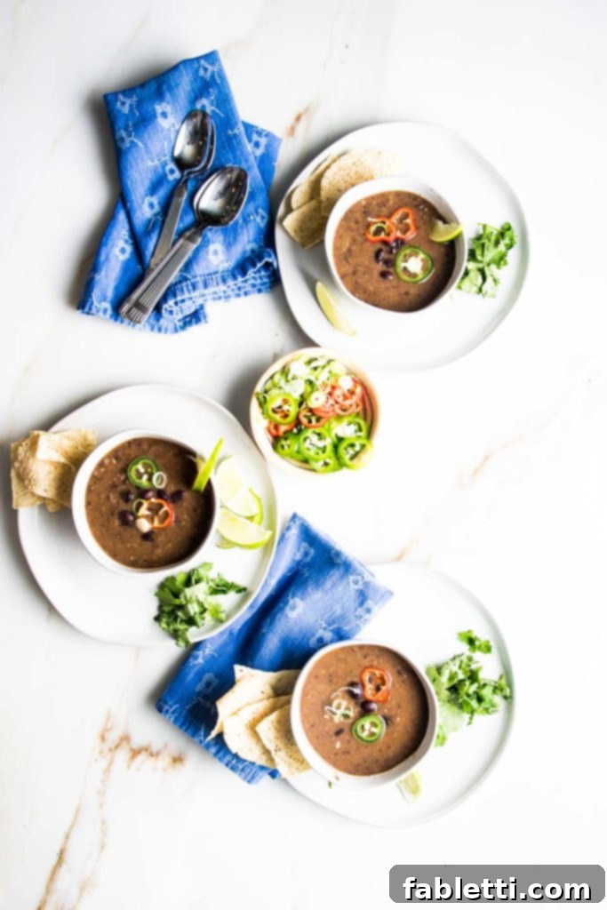 No-Fuss Black Bean Soup 13 Three colorful bowls of vegan black bean soup, each adorned with a unique array of fresh toppings like avocado, cilantro, and red onions, inviting a delightful meal.