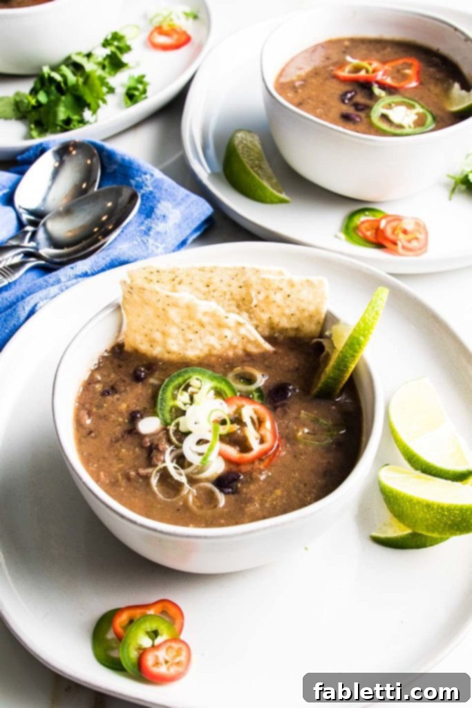No-Fuss Black Bean Soup 3 Two bowls of vibrant black bean soup, beautifully topped with fresh avocado, cilantro, and red onions, showcasing its colorful appeal.