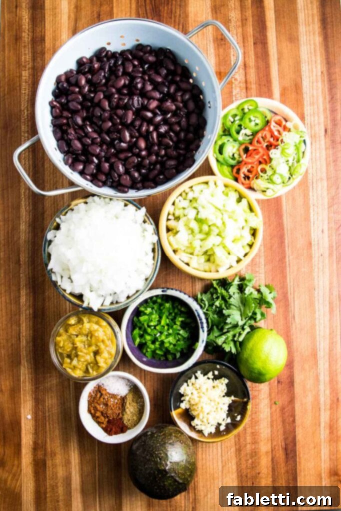 No-Fuss Black Bean Soup 4 A vibrant display of fresh ingredients for black bean soup: black beans, neatly chopped onions, an assortment of aromatic spices, fresh scallions, canned green chilis, fragrant cilantro, a bright lime, minced garlic, and a fiery jalapeno.