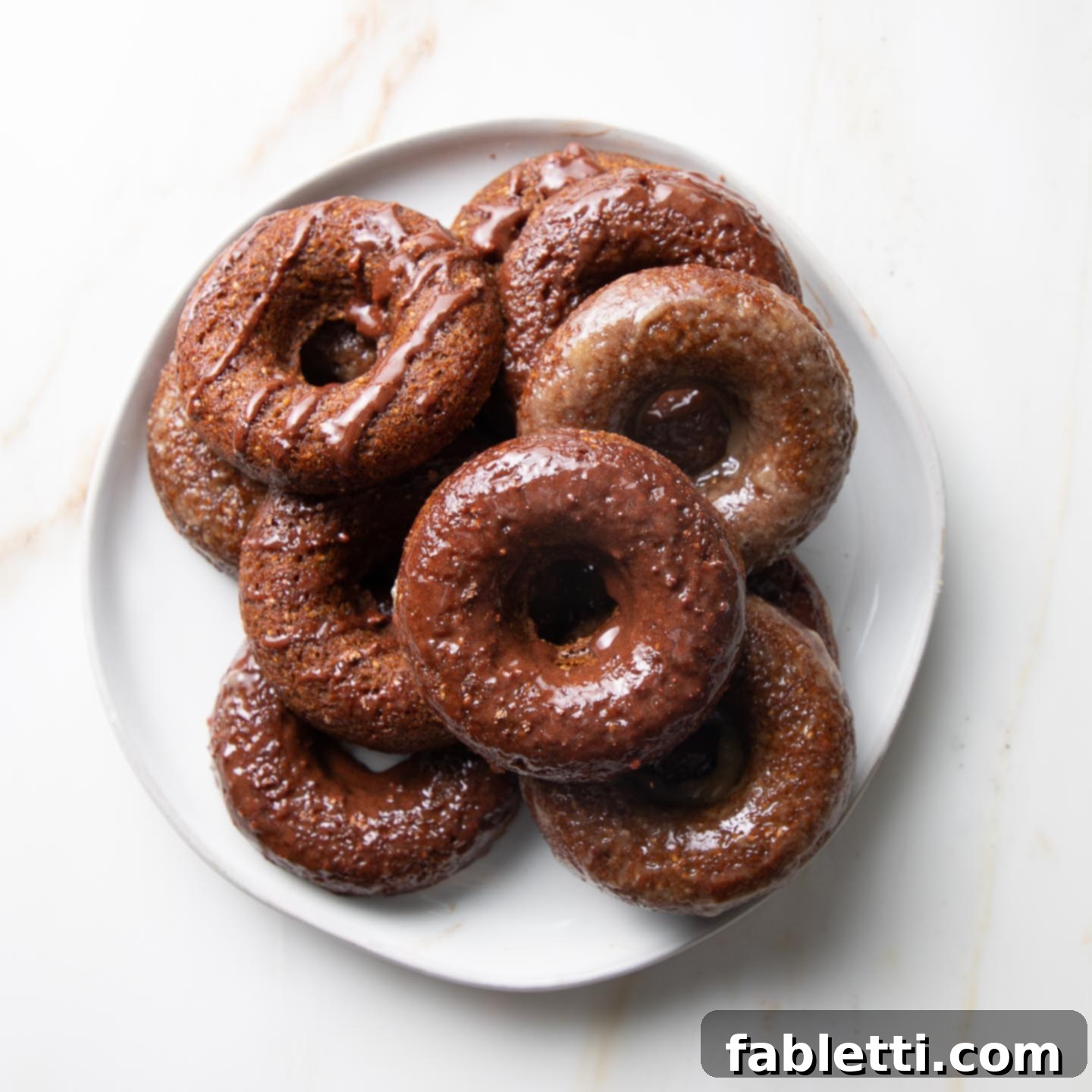 Gluten-Free Baked Pumpkin Spice Doughnuts 2 A plate of glazed pumpkin donuts, beautifully arranged and ready to eat.