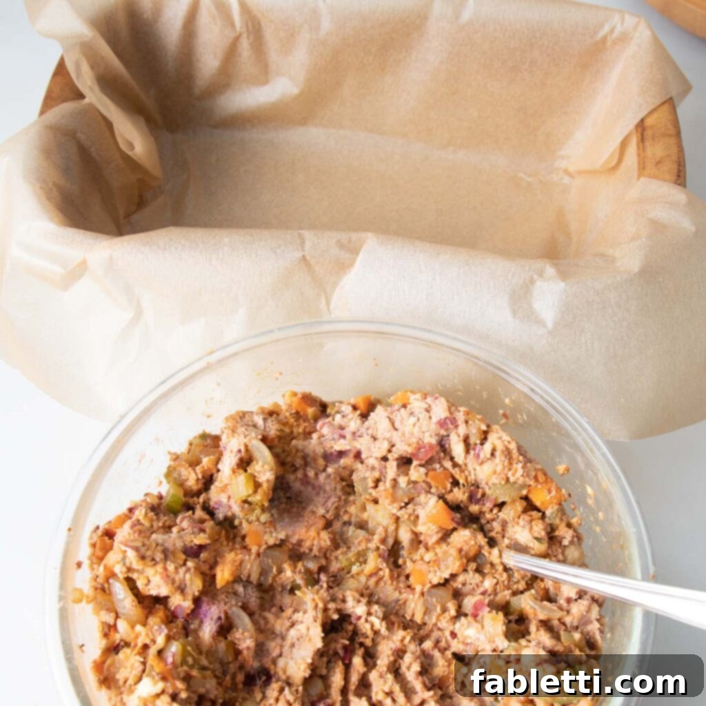 Hearty Plant-Based Meatloaf 11 A glass bowl with the mashed bean mixture positioned next to a loaf pan that has been perfectly lined with unbleached parchment paper.