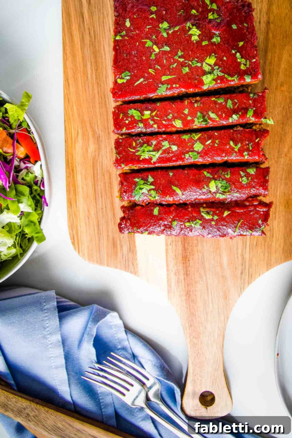 Hearty Plant-Based Meatloaf 16 A delicious vegan meatloaf, adorned with a glossy tomato glaze and fresh herbs, cut into thick, inviting slices.