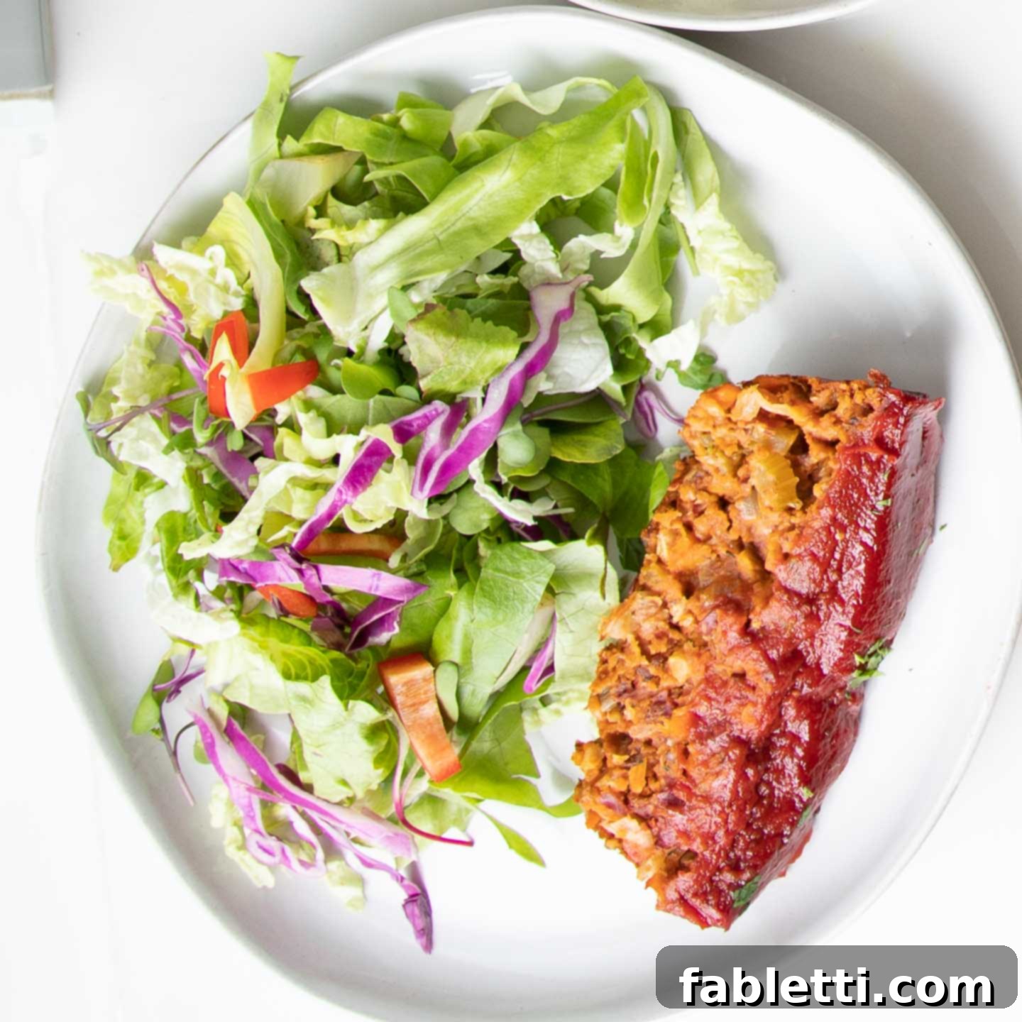 Hearty Plant-Based Meatloaf 18 A simple yet elegant plate featuring a slice of vegan meatloaf served with a fresh green salad.