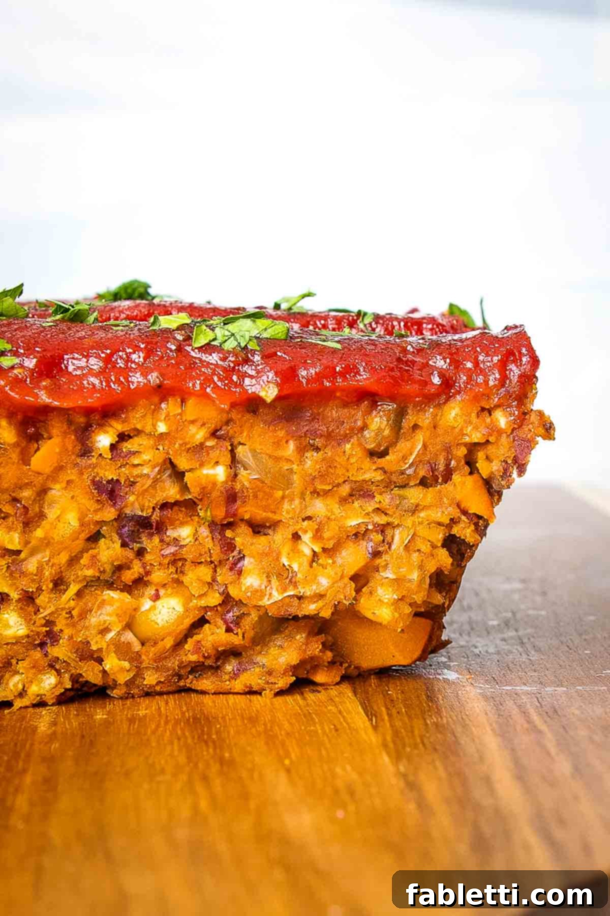 Hearty Plant-Based Meatloaf 4 A side view of a delectable slice of vegan meatloaf, generously topped with a homemade tomato glaze.