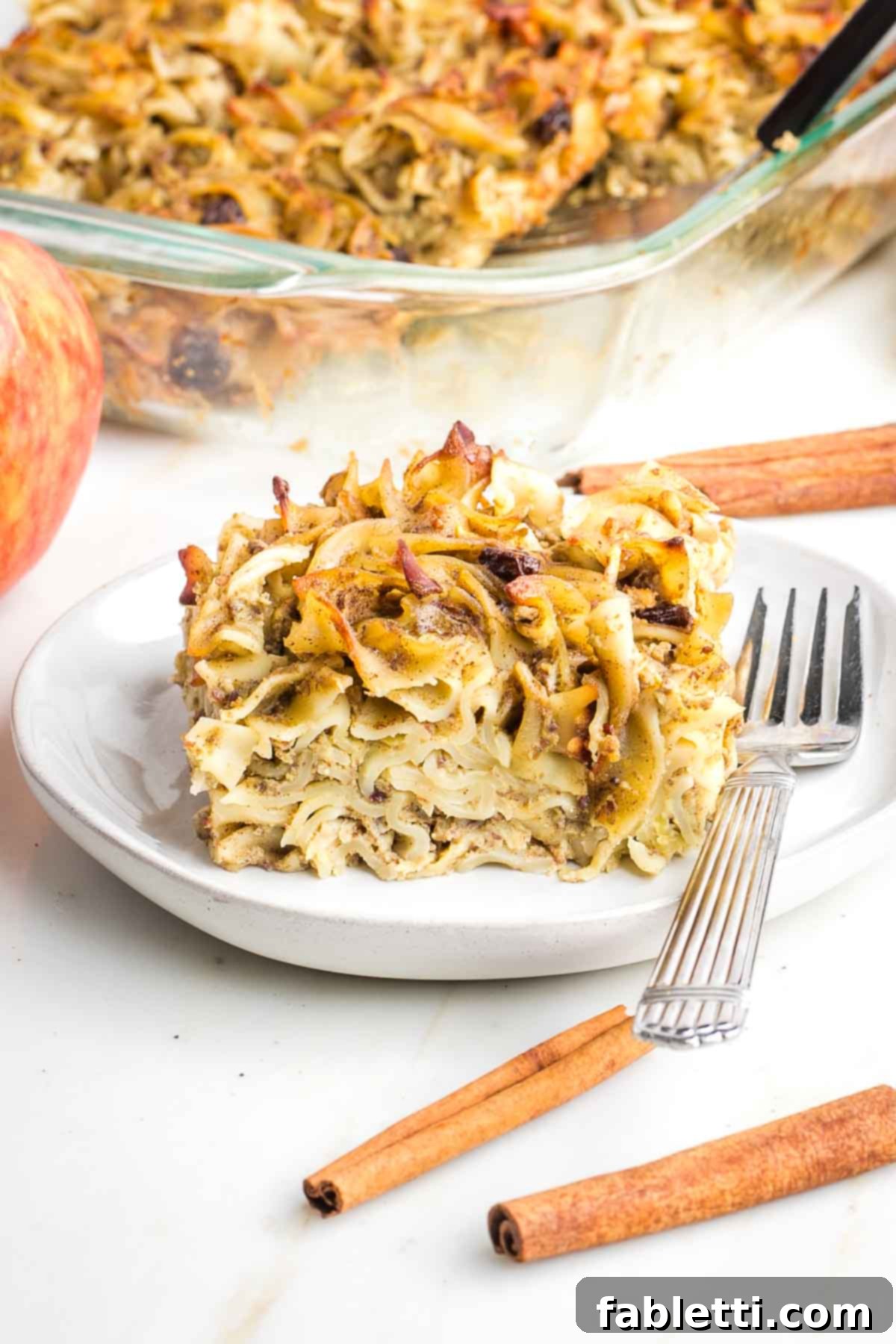 Delicious Dairy-Free Apple Noodle Kugel 15 A close-up of a rustic wooden surface with small baking ingredients like cinnamon sticks and dried cranberries scattered, suggesting the rich, warm flavors and preparation details for a homemade dish.