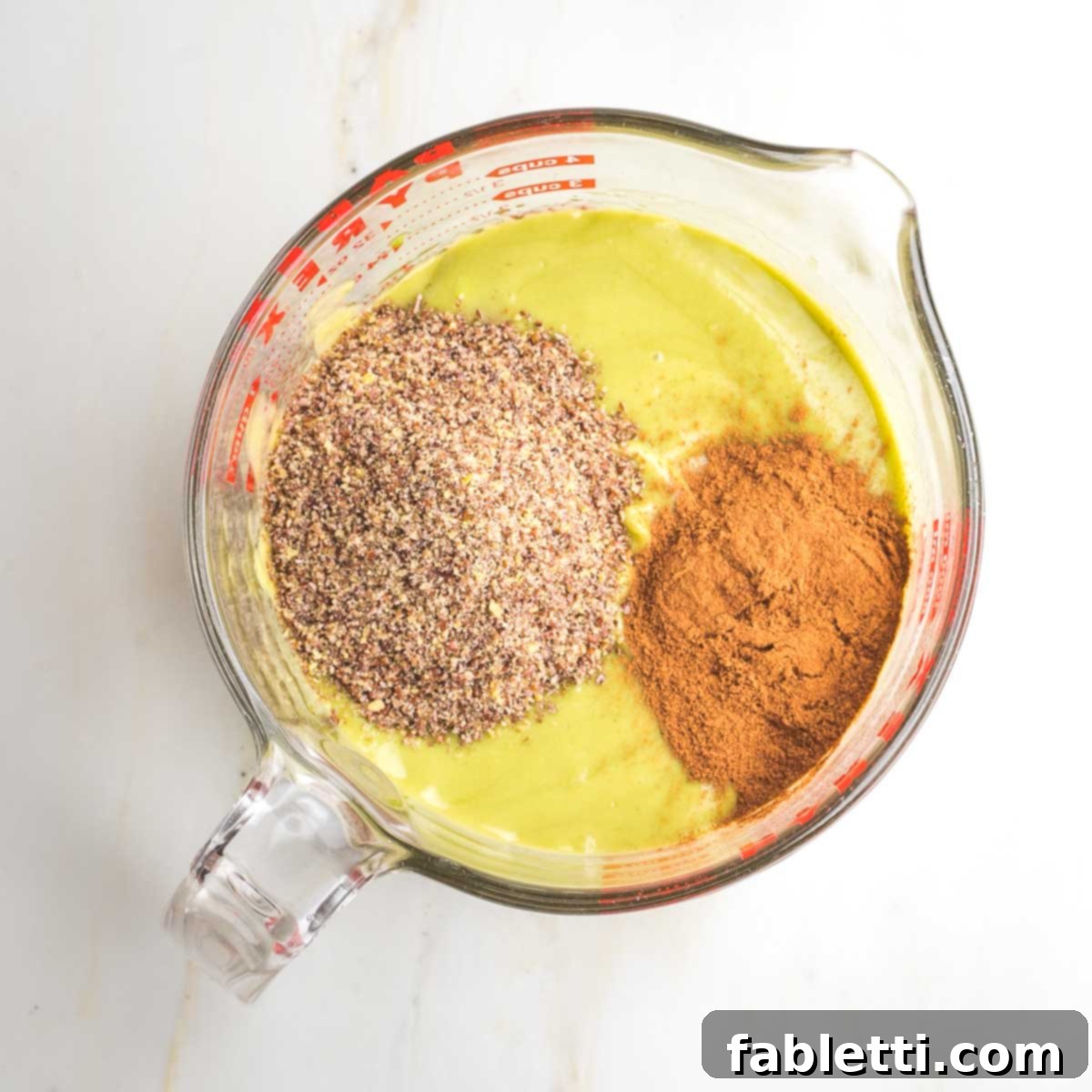 Delicious Dairy-Free Apple Noodle Kugel 6 The creamy, light green avocado custard base is now being enhanced with the addition of ground flaxseed and aromatic cinnamon, preparing it for the final blend.