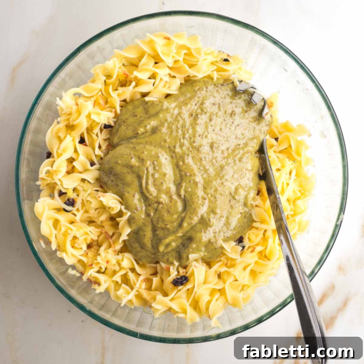 Delicious Dairy-Free Apple Noodle Kugel 10 Cooked noodles are mixed into the large bowl with shredded apples and raisins, then the creamy, brownish 'pudding' mixture is poured over, ready to be fully combined.