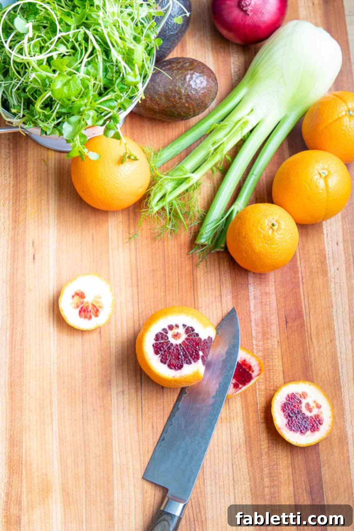 Radiant Orange Fennel 5 Demo on how to cut the peel off an orange with other colorful produce in the background.