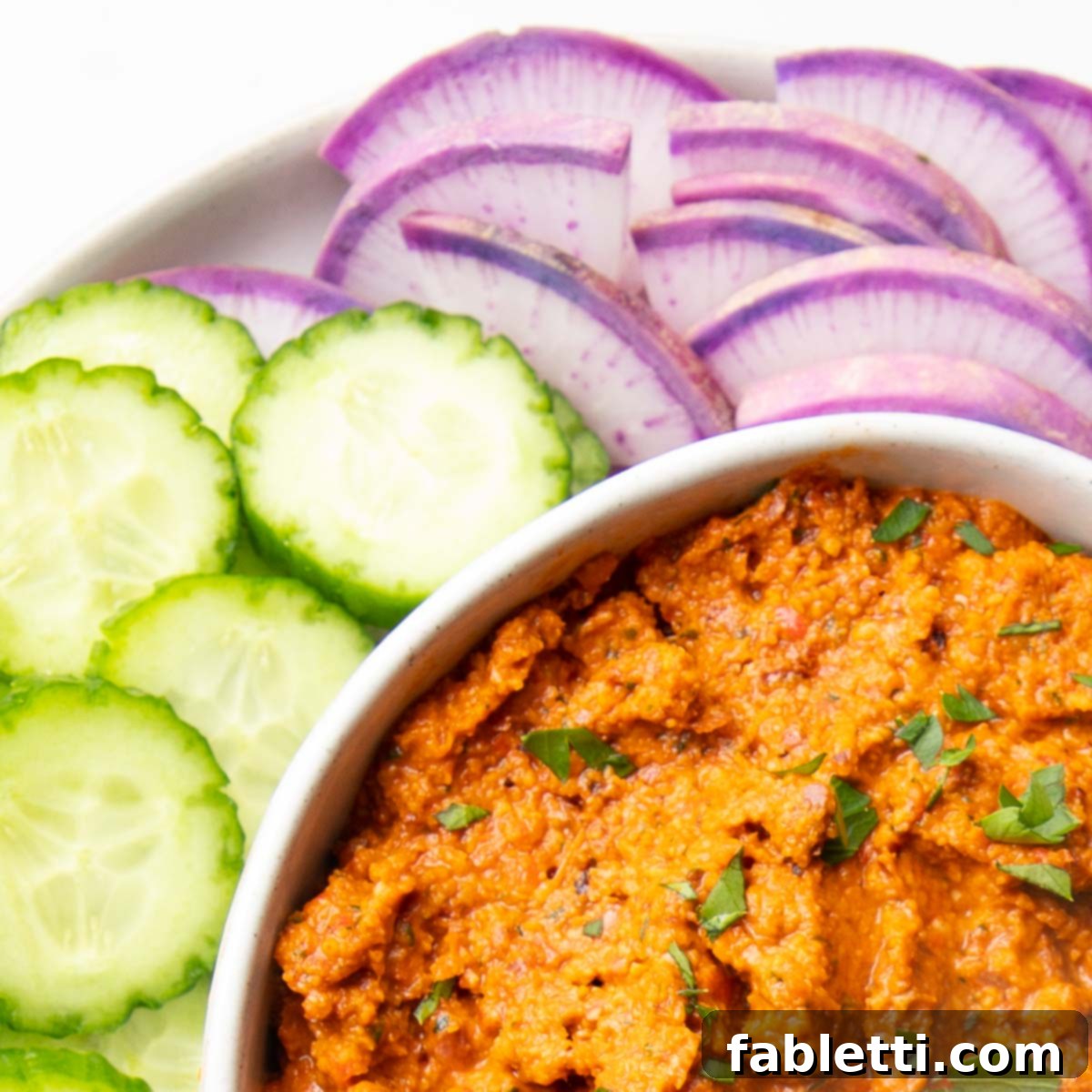 Vibrant Oil-Free Romesco 3 A rustic, rust-colored Romesco spread, generously served alongside an array of colorful, fresh vegetables.