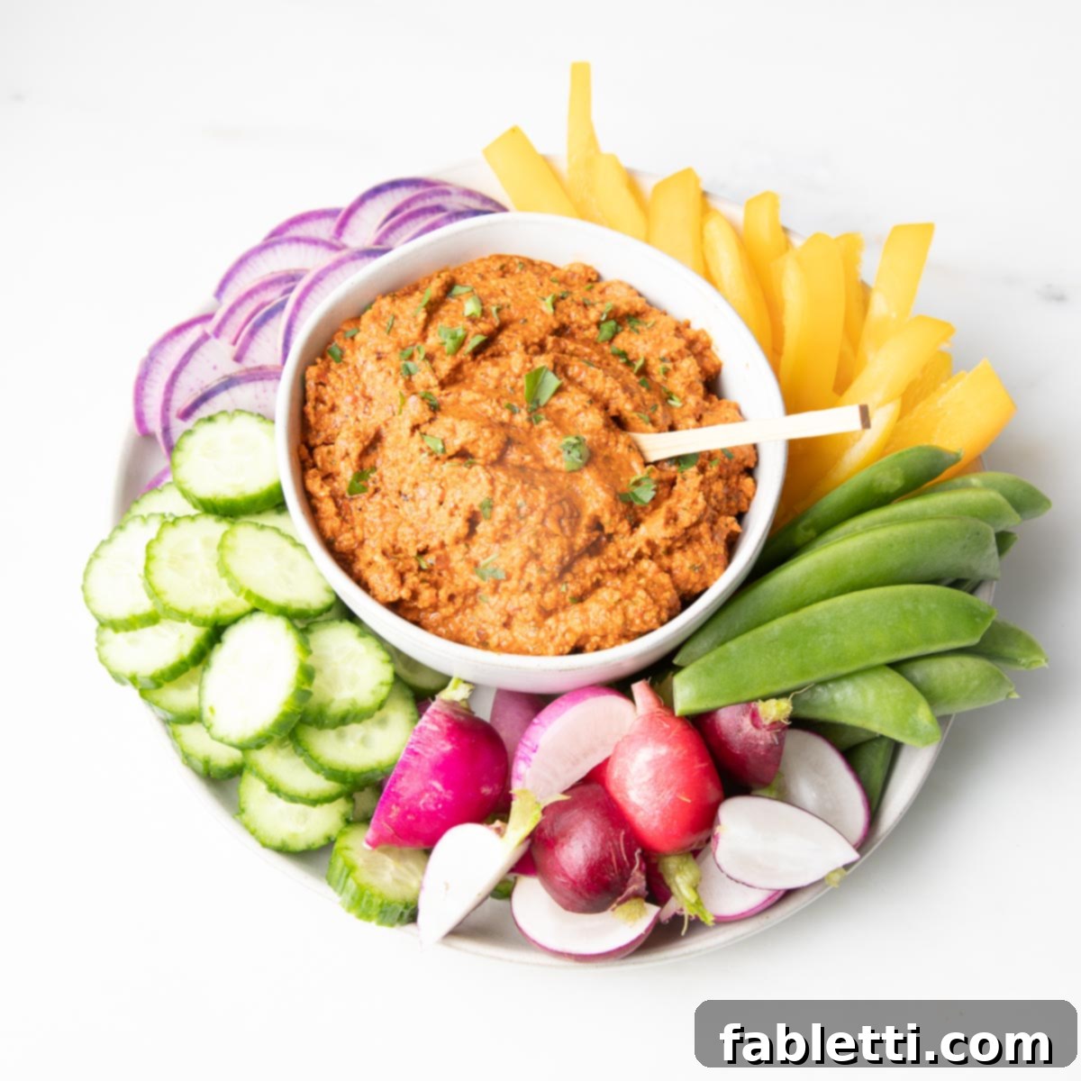 Vibrant Oil-Free Romesco 7 A vibrant selection of colorful vegetables beautifully arranged around a central bowl of Romesco dip, creating an inviting spread.